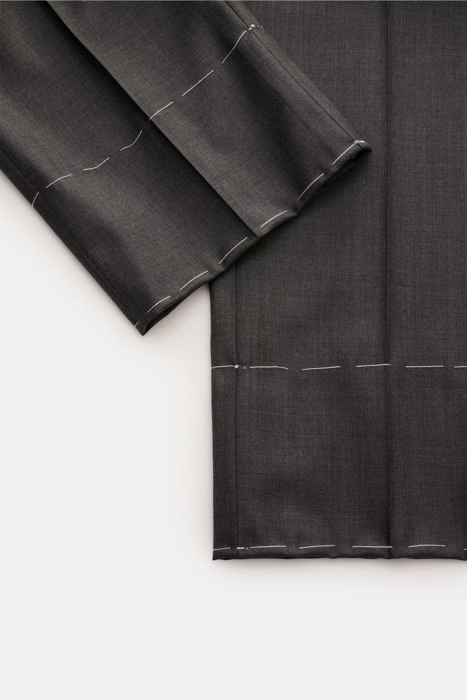 Brioni Anzug 'Brunico' dunkelgrau meliert shown from a close-up top view, highlighting fine woven twill wool fabric and unfinished sleeve hems.