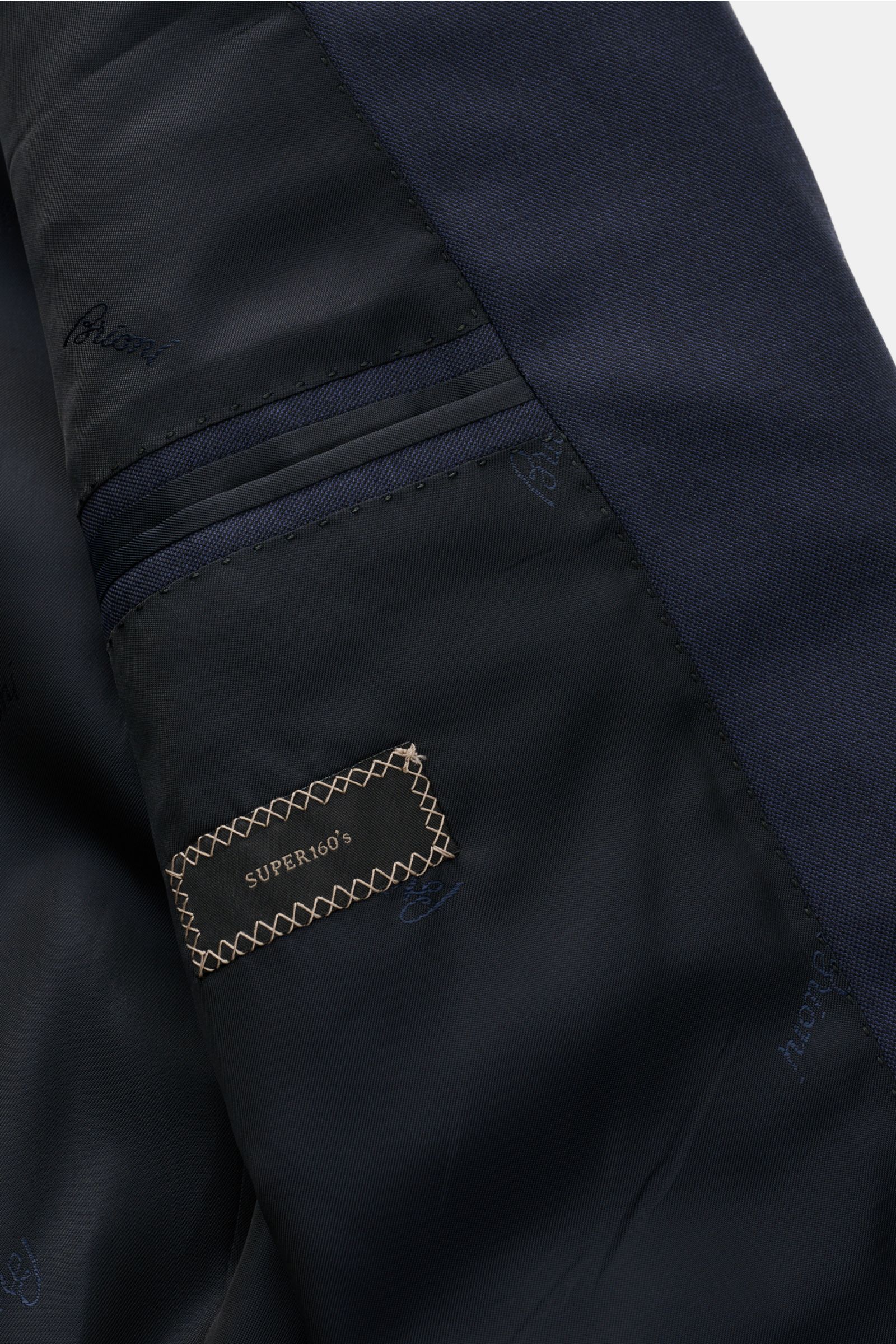 Close-up inside view of the Brioni Anzug 'Brunico' dark navy suit jacket showing Super 160'S wool label and branded lining, highlighting fine craftsmanship and smooth fabric.

Eleganz aus dem Hause BRIONI: Mit dem in Italien gefertigten Anzug 'Brunico'