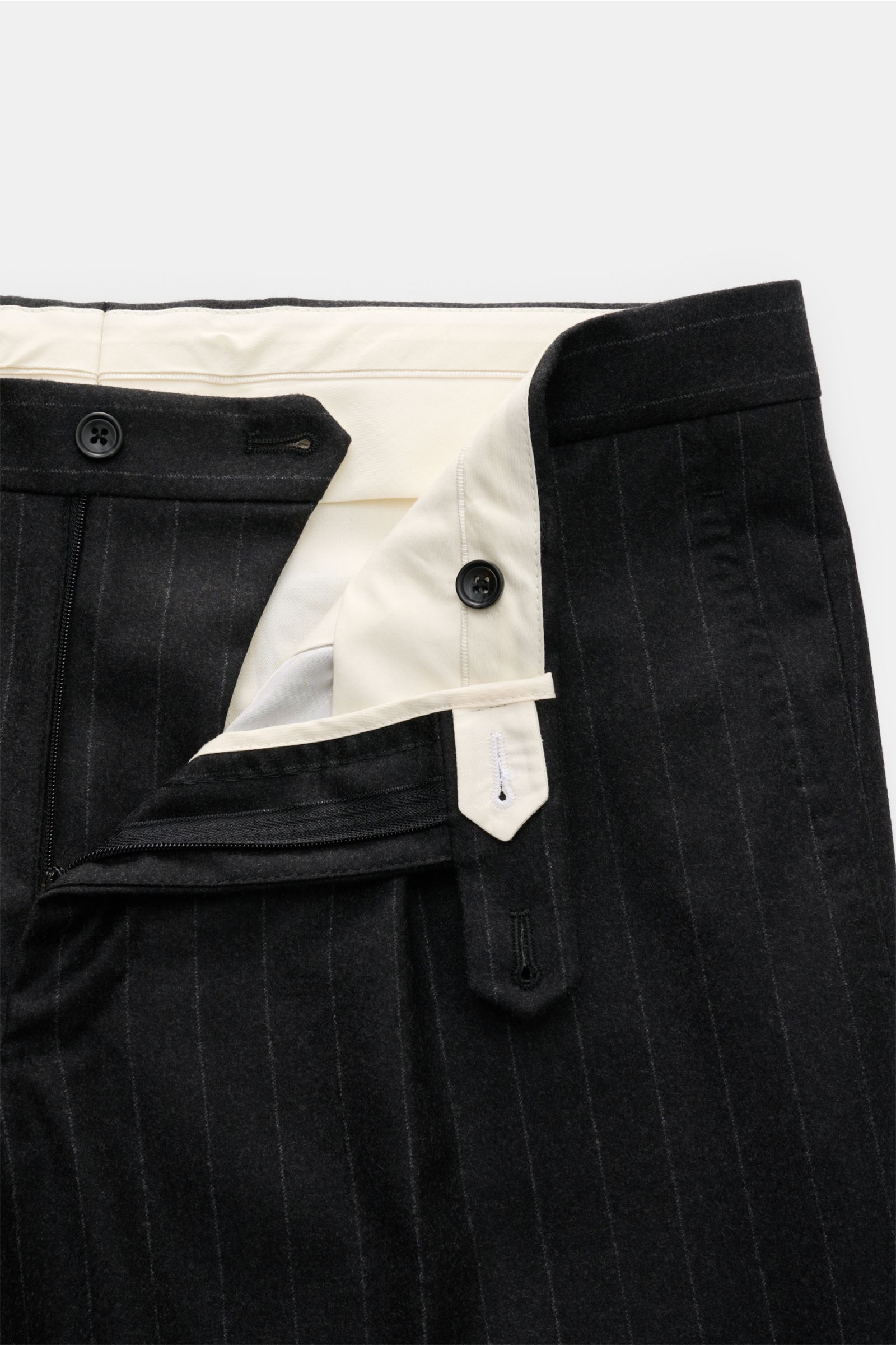 Close-up front view of the waistband and fly of the Tagliatore Anzug 'Vesuvio' anthrazit gestreift trousers in dark pinstripe wool, showing button and zipper details. Zeitgenössisches Design trifft italienische Tradition aus dem Hause TAGLIATORE: Mit dem 