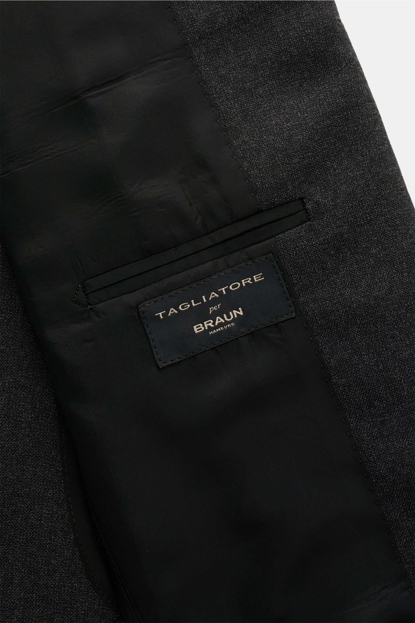 Close-up inside view of the Tagliatore Anzug 'Vesuvio' anthrazit meliert showing the black inner lining, pocket, and brand label stitched on the half-lined pure wool suit jacket. Zeitgenössisches Design trifft italienische Tradition aus dem Hause TAGLIATO