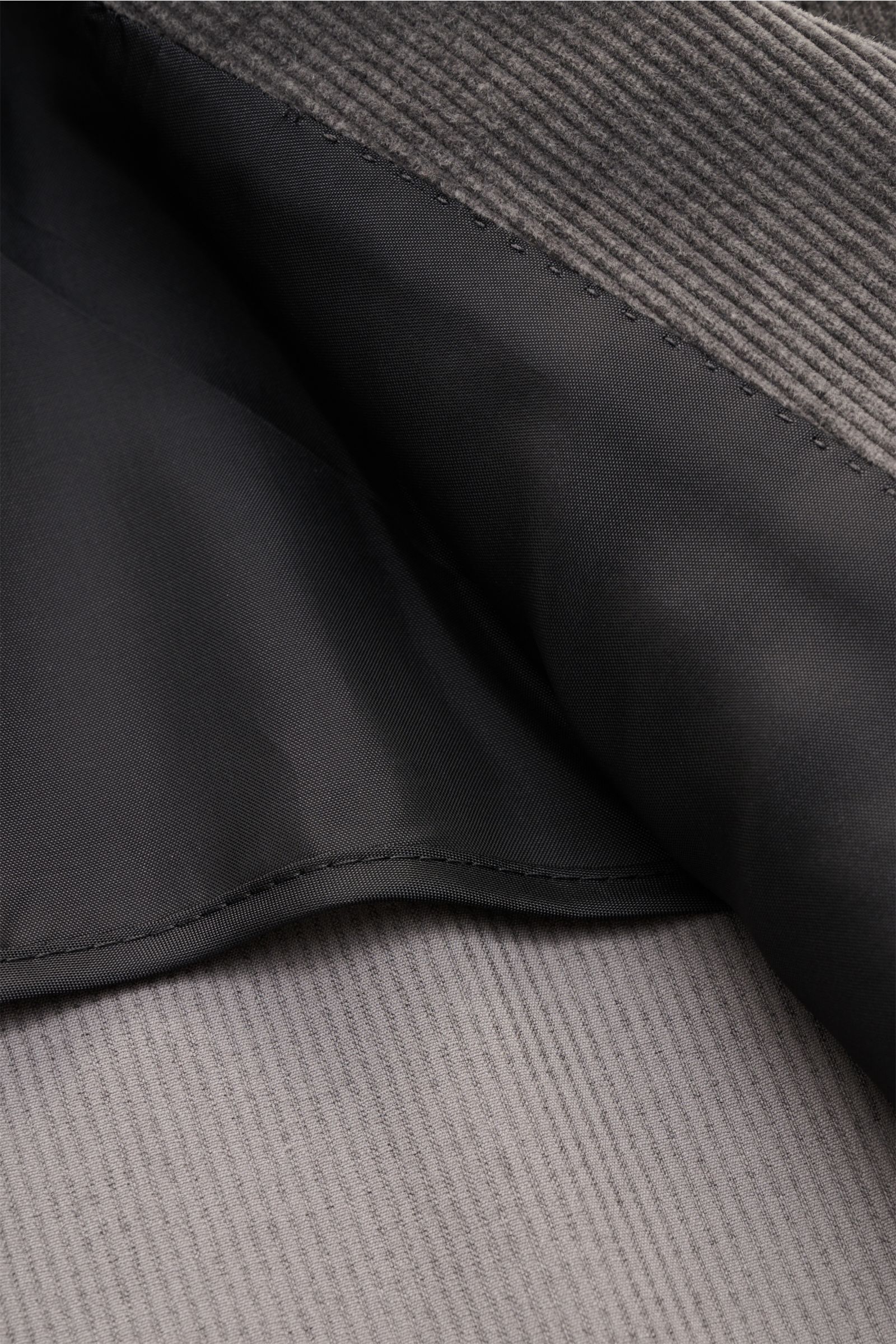 Close-up image of the inside lining and beige cord fabric of the Tagliatore Cordanzug beige, showing the soft cotton and wool cord with a smooth black inner lining, photographed from above. The stylish suit features a slim fit, unconstructed design with a