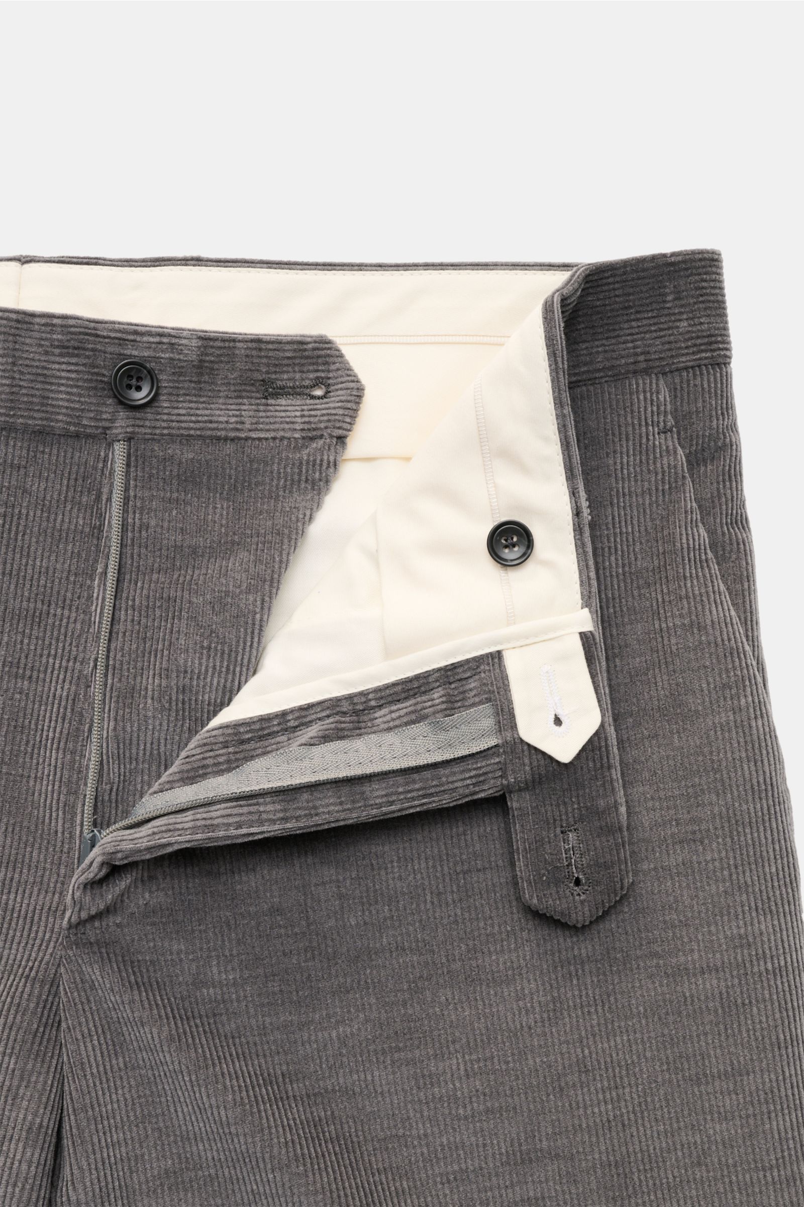 Close-up front view of the zipper and button fastening of the Tagliatore Cordanzug beige pants, made of soft cotton and wool corduroy with a slim fit, high waistband, elastic drawstring, and side seam pockets. The unconstructed design suit features a slim