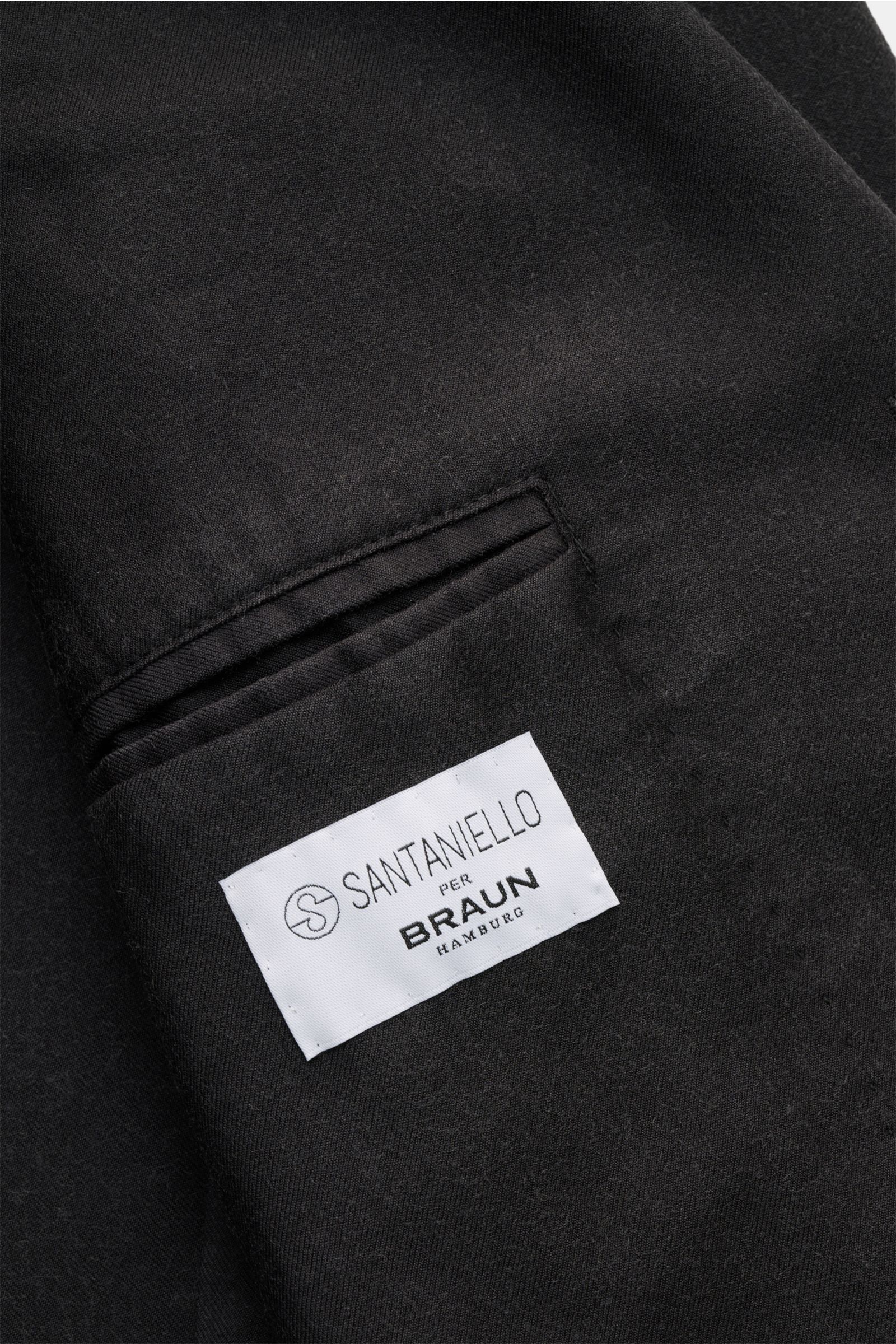 Close-up interior view of the Santaniello Anzug dunkelgrau showing the white fabric label sewn above a welt pocket, highlighting its pure Super 110's wool and soft touch.