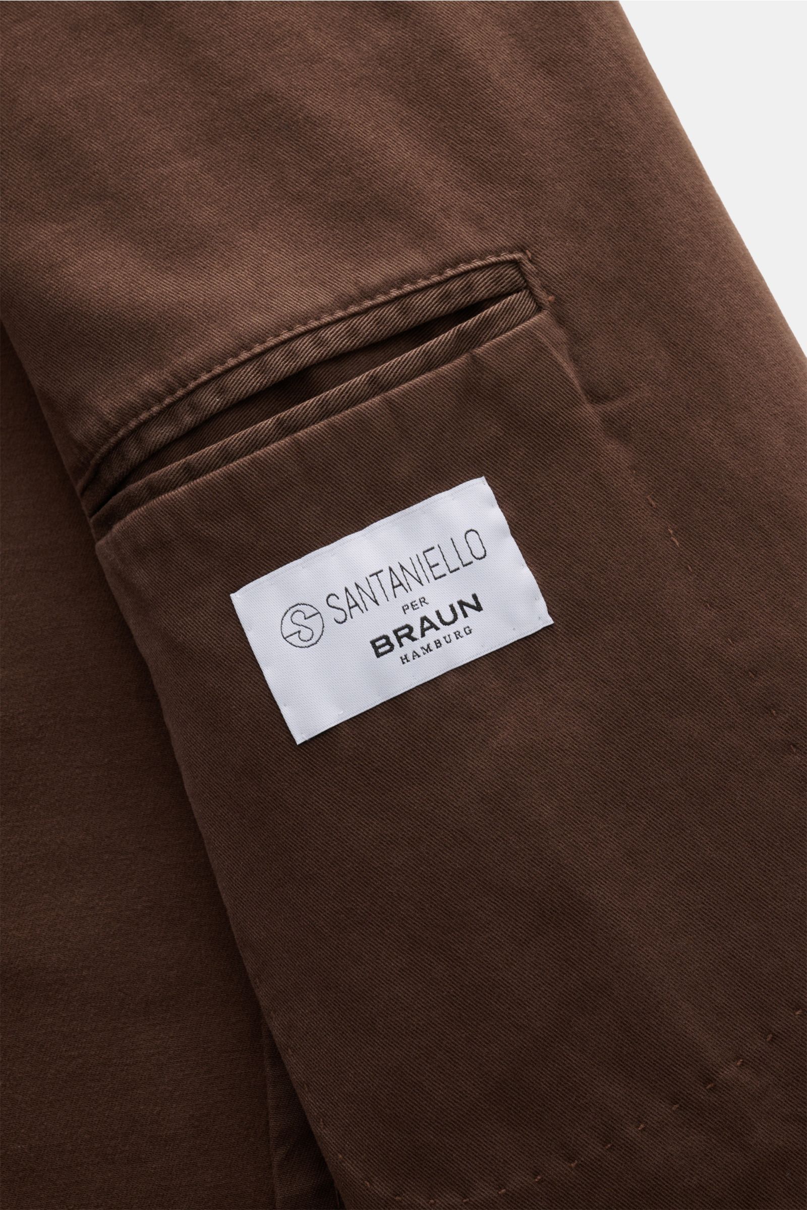 Close-up view of the taupe Santaniello Anzug showing the soft elastic cotton twill fabric and white label on the inner pocket.