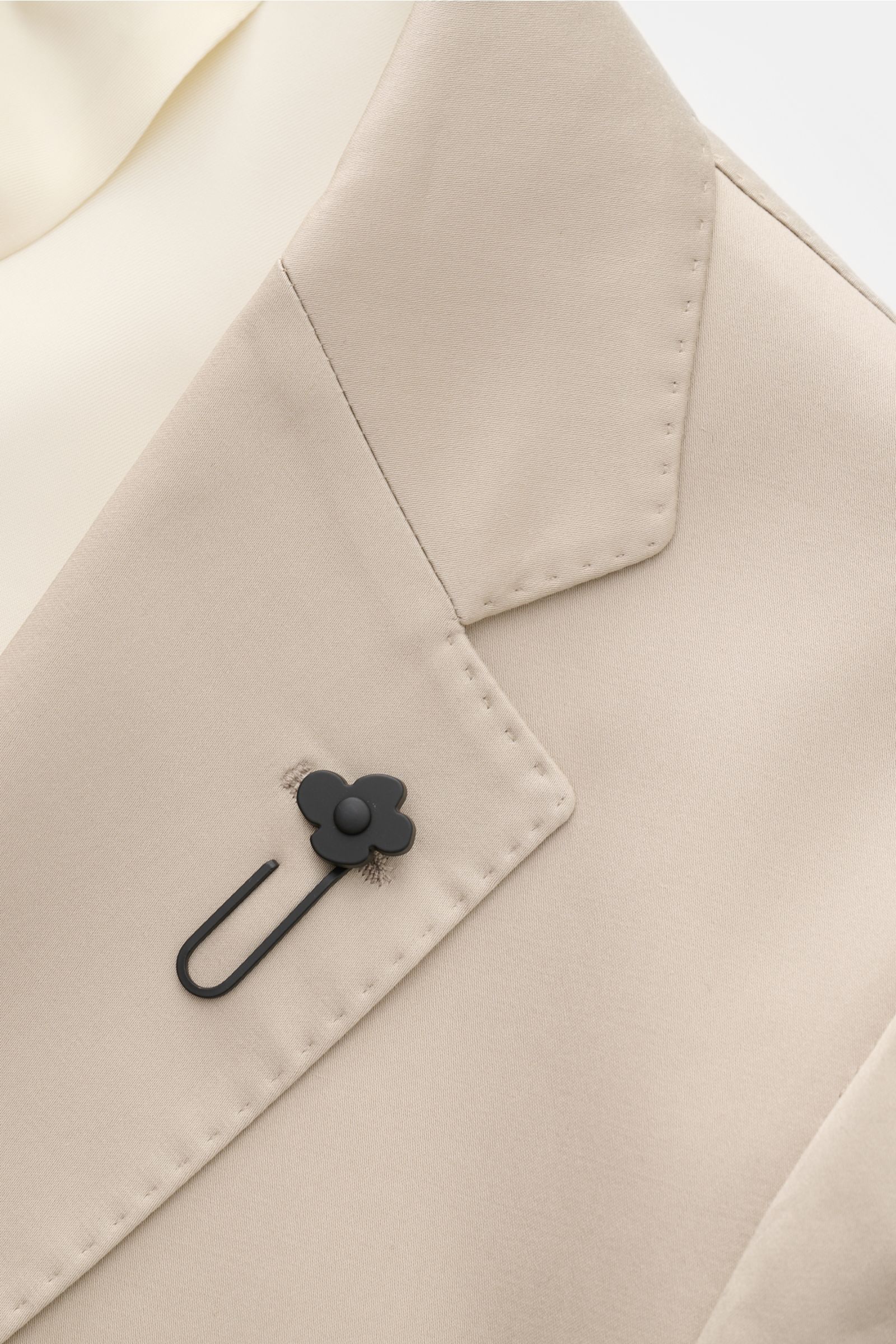 Nahaufnahme des fallenden Revers mit Blütenpin am Slim Fit Lardini Anzug beige aus elastischer, weicher Baumwolle.