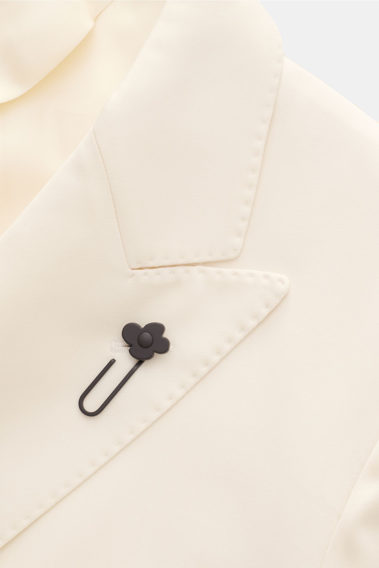 Close-up front view of Lardini Anzug creme lapel in pure virgin wool with slim fit, floral black pin on iconic notch lapel, soft texture.