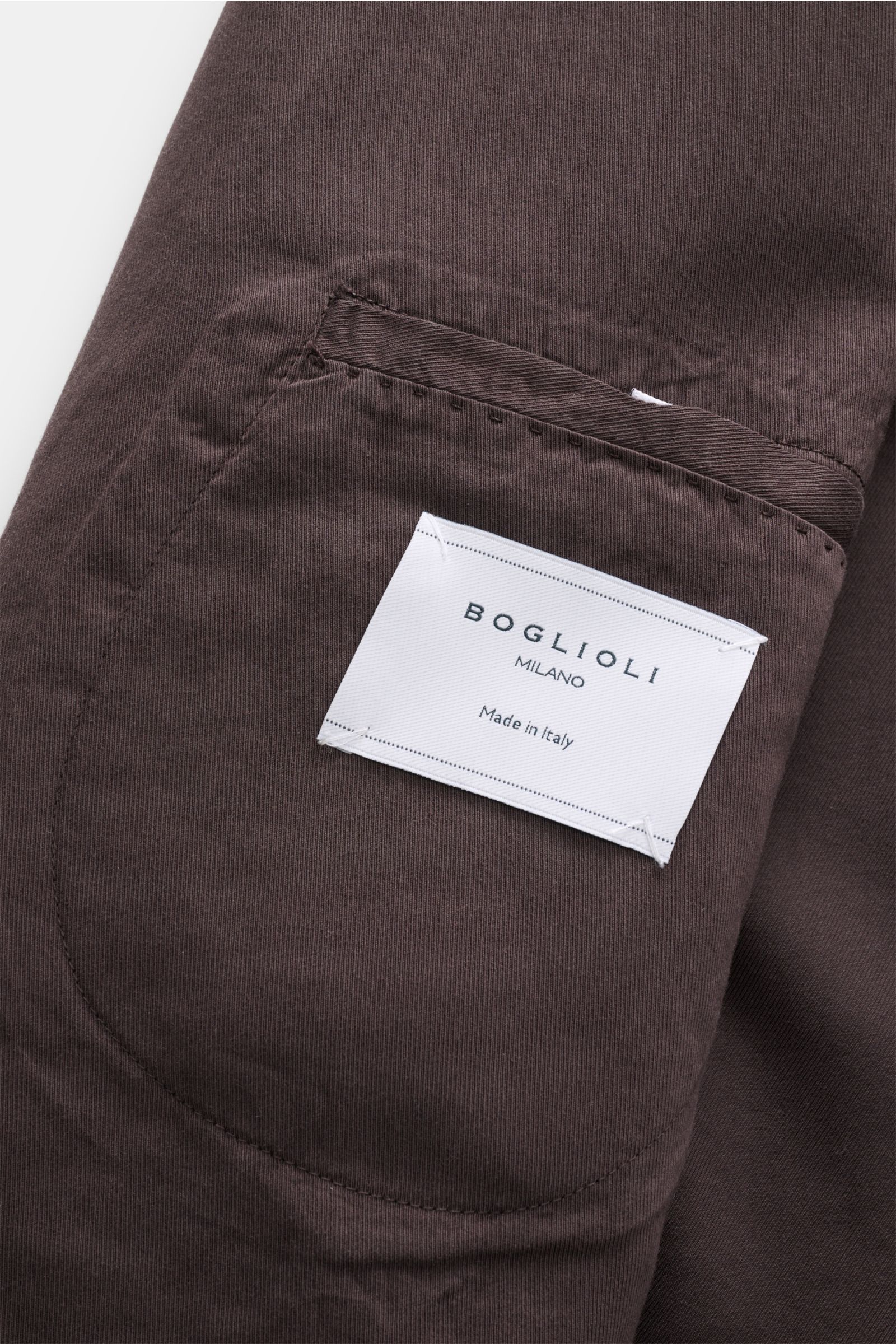 Nahaufnahme der Innentasche mit weißem Boglioli Etikett am dunkelbraunen Boglioli Anzug 'K. Jacket' aus Baumwolle und Seide.