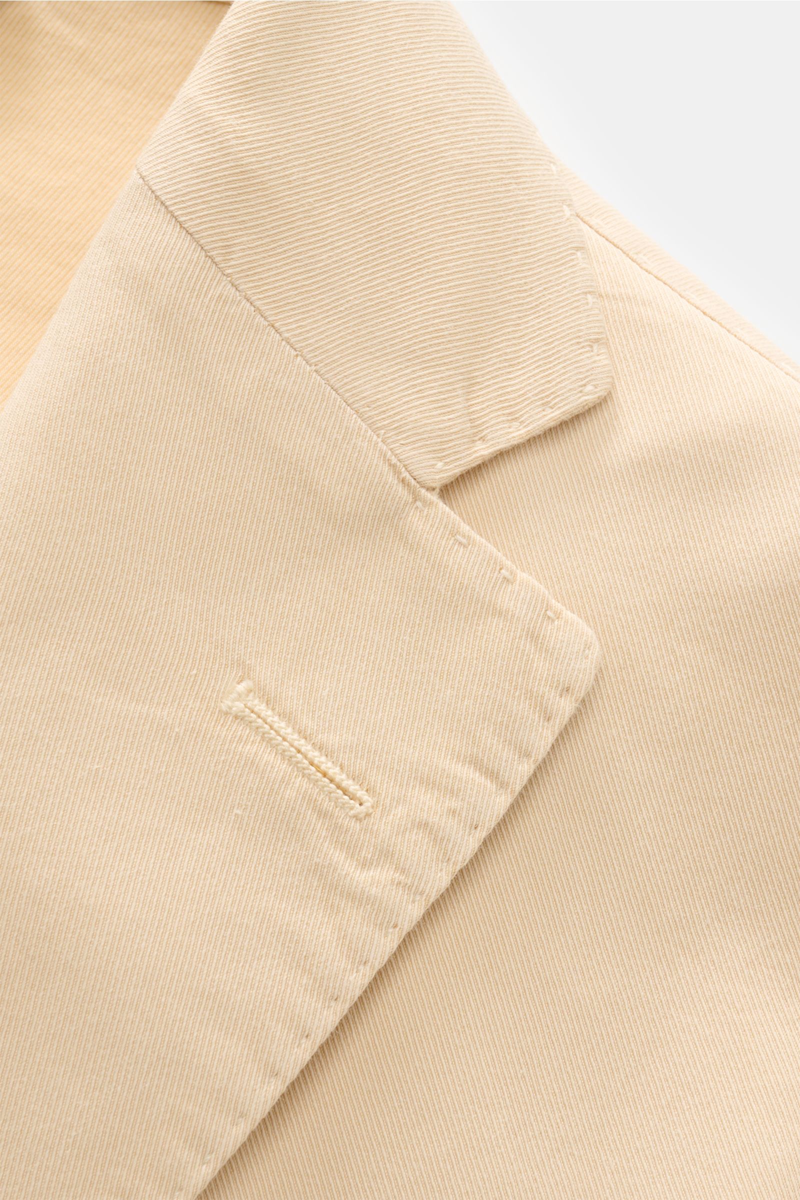 Nahaufnahme des fallenden Reverses des Boglioli Anzugs 'K. Jacket' sand in Twill aus Baumwolle und Seide, fotografiert aus schräger Draufsicht.