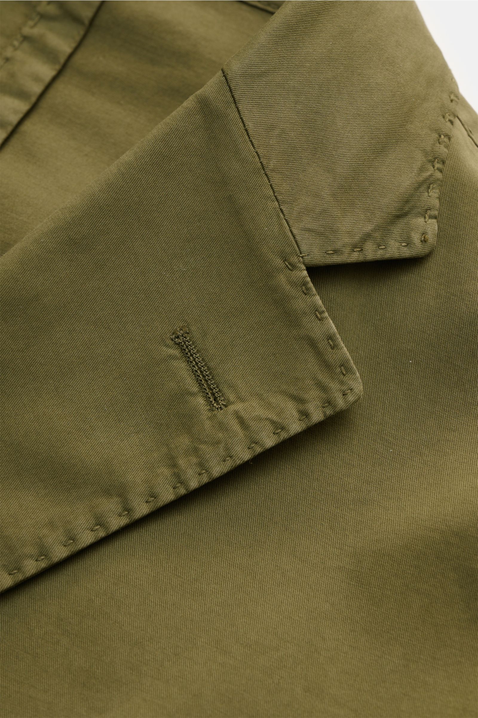Nahaufnahme des olivfarbenen Boglioli Anzugs 'K. Jacket', Fokus auf fallendes Revers mit handgenähten Details, Baumwoll-Twill, Slim Fit, leicht elastisch.