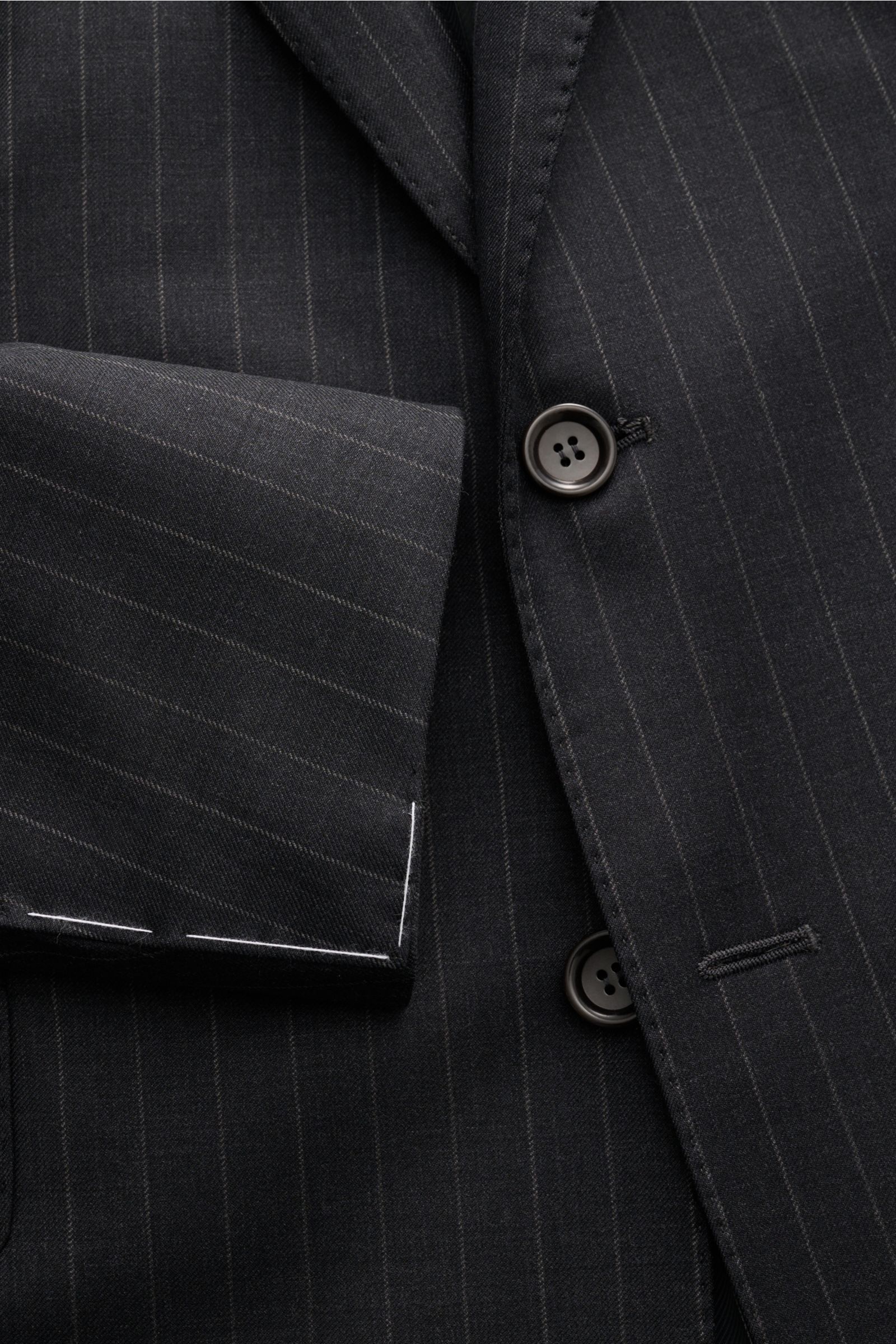 Nahaufnahme des Stile Latino Anzugs 'Vincenzo' anthrazit gestreift, seitlich fotografiert, feine Wolle, Slim Fit, Drei-Knopf-Sakko mit fallendem Revers und Button-Fly-Hose.