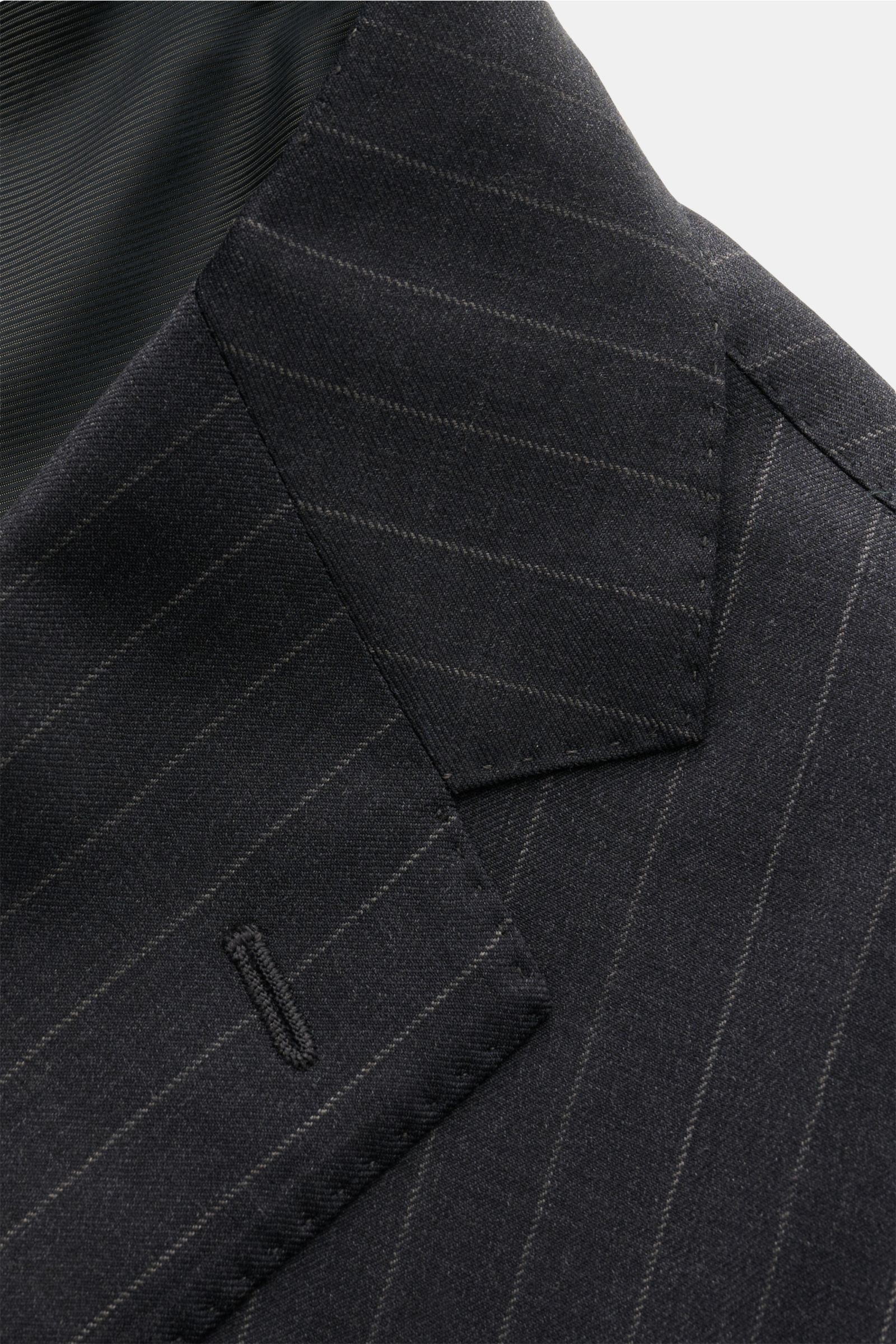 Nahaufnahme des fallenden Revers und der Brusttasche des Stile Latino Anzugs 'Vincenzo' anthrazit gestreift aus feinem Twill, weicher Wolle, Slim Fit, fotografiert aus schräger Perspektive.