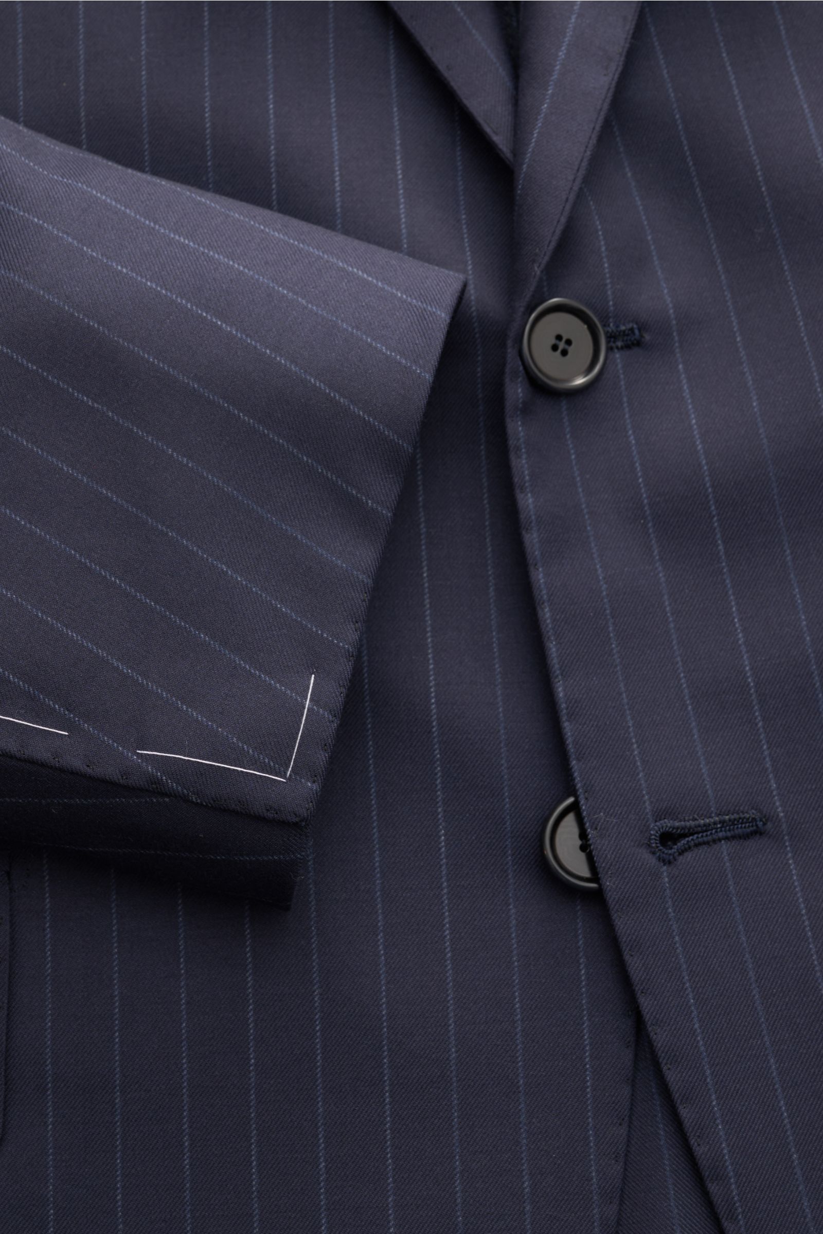 Cesare Attolini Anzug navy gestreift aus Super 160'S Wolle, Slim Fit, mit feinen Nadelstreifen, Drei-Knopf-Sakko und Ärmel mit weißen Heftfäden, Detailaufnahme.