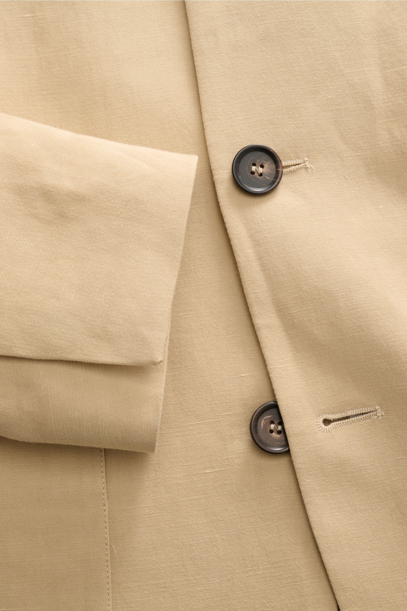 Close-up front view of Doppiaa Anzug 'Aanetoant' beige jacket showing smooth Lyocell-linen fabric, soft texture, five-button style, variable collar, and concealed sleeve buttons, highlighting its unconstructed design and comfortable summer tailoring.