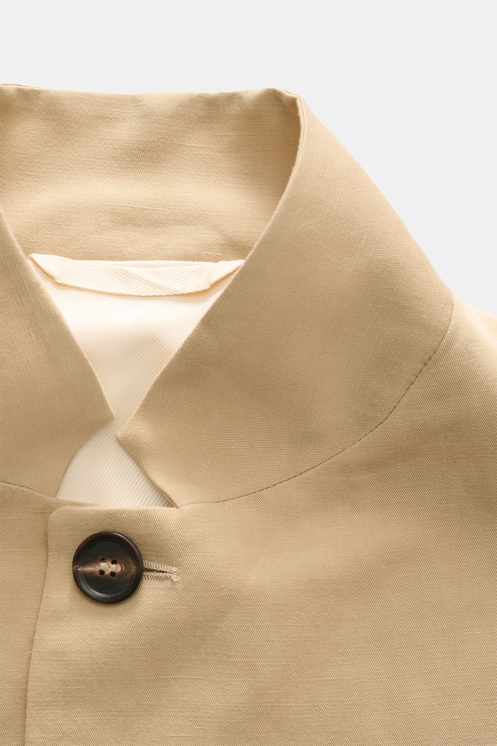 Beige collar and top button detail of Doppiaa Anzug 'Aanetoant' beige, photographed from a close-up, front angle. Summer tailoring in a soft Lyocell-linen mix with a regular fit, unconstructed design, five-button jacket, variable collar, hip pockets, hidd