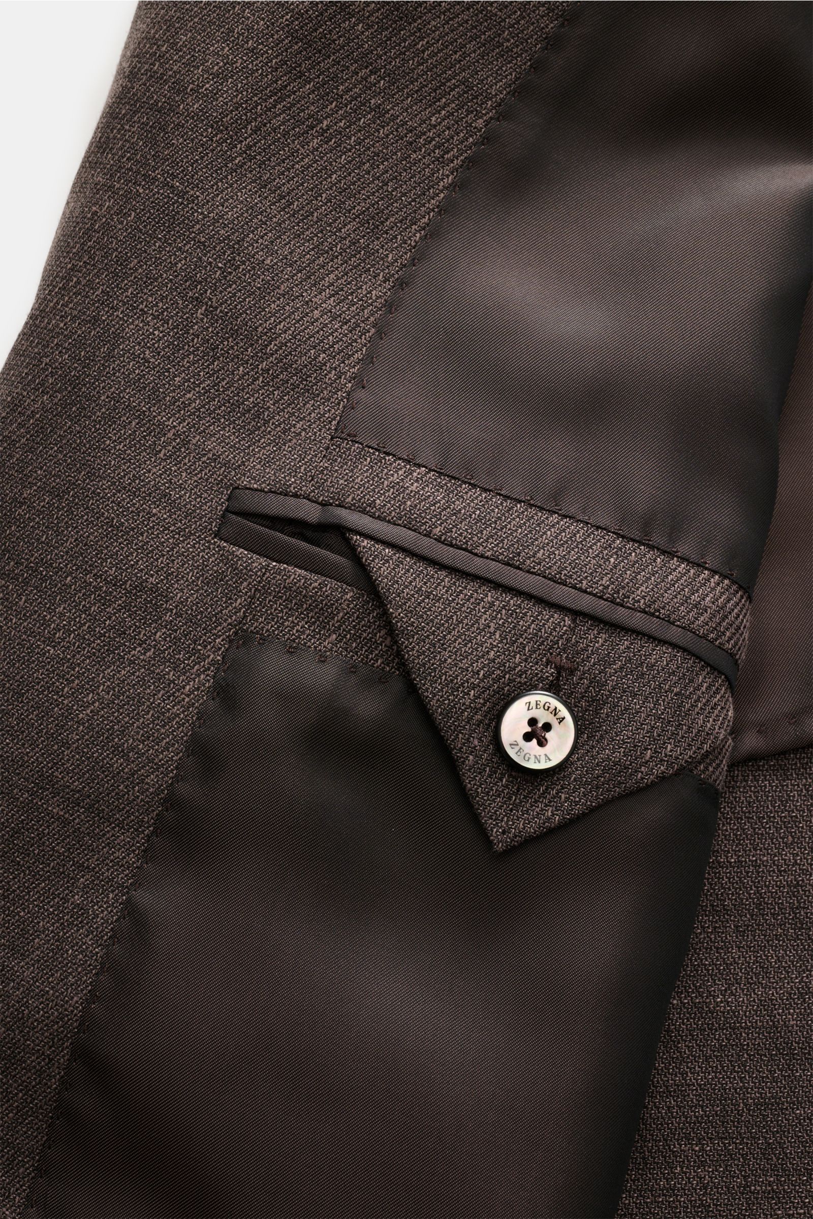 Close-up view of the interior pocket and button detail of the Zegna Anzug 'Natural' dunkelbraun meliert, showcasing its fine wool, linen, and silk blend fabric with smooth lining, tailored craftsmanship, and elegant finishing. Souveräne Eleganz auf höchst