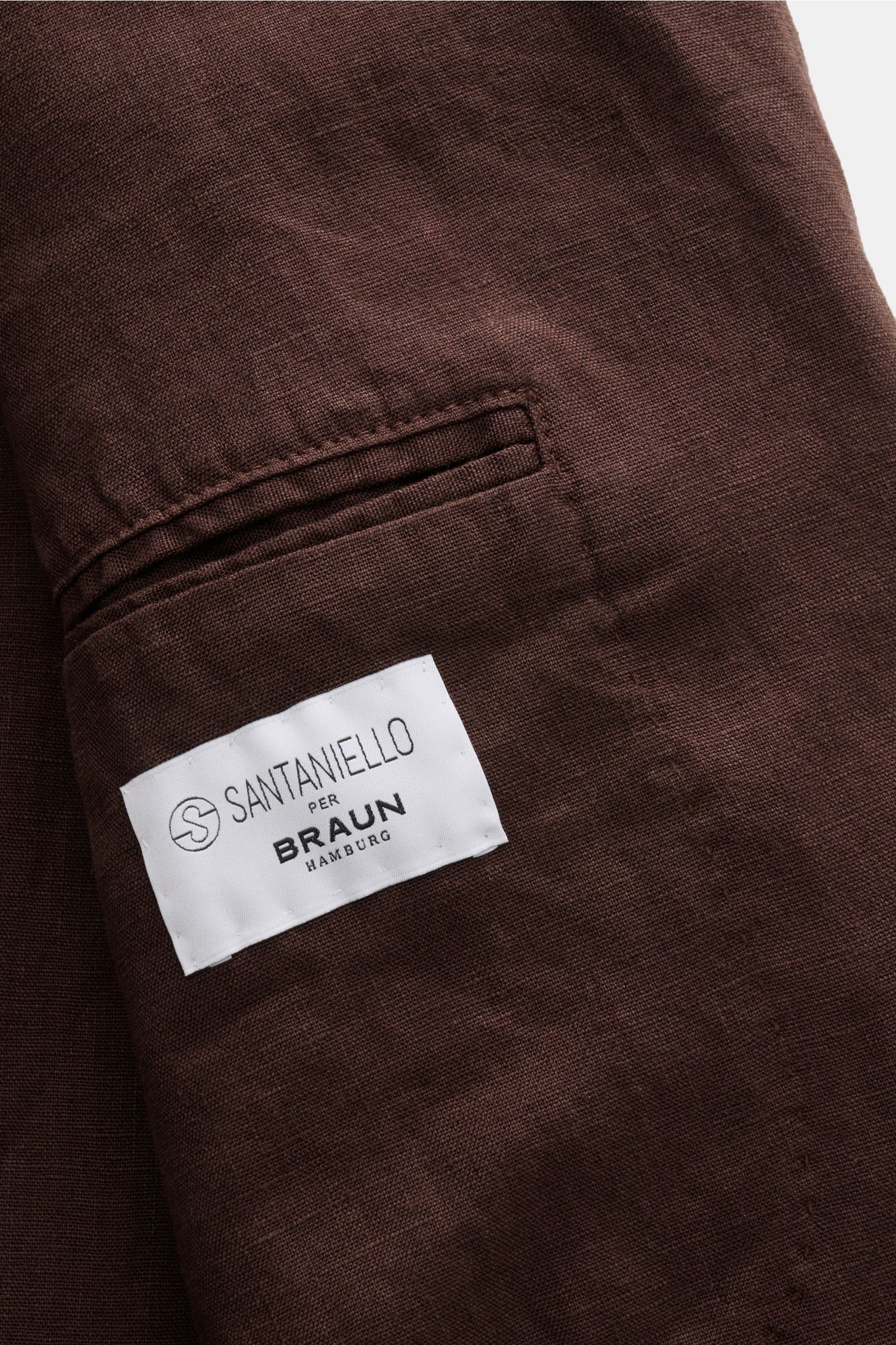Nahaufnahme des braunen Santaniello Anzugs aus reinem Leinen, Detailansicht der paspelierten Gesäßtasche mit Markenlabel, weicher Griff.