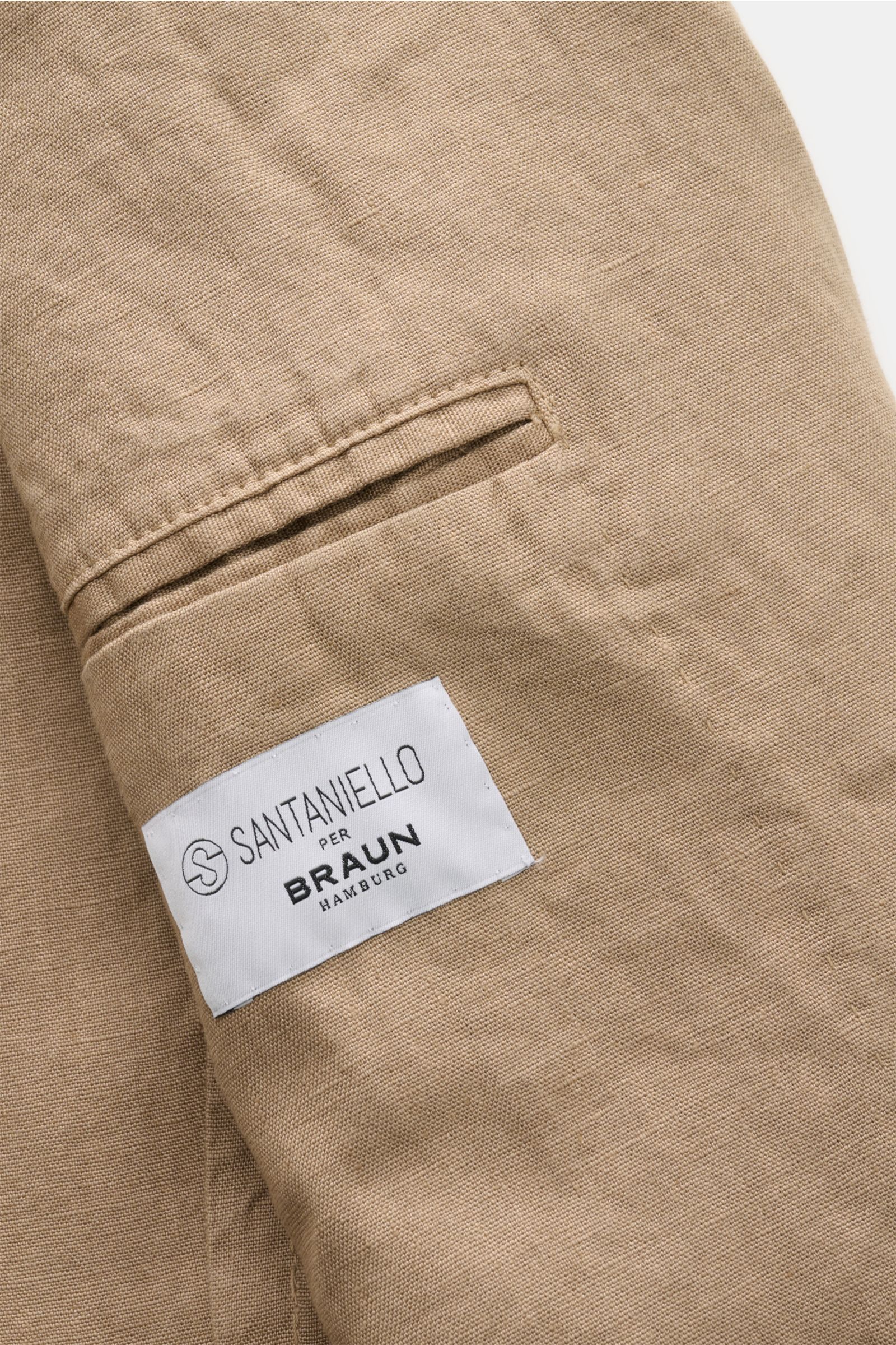Nahaufnahme einer paspelierten Gesäßtasche des Santaniello Anzug taupe aus reinem Leinen mit weichem Griff und sichtbarem Markenlabel Braun Hamburg.