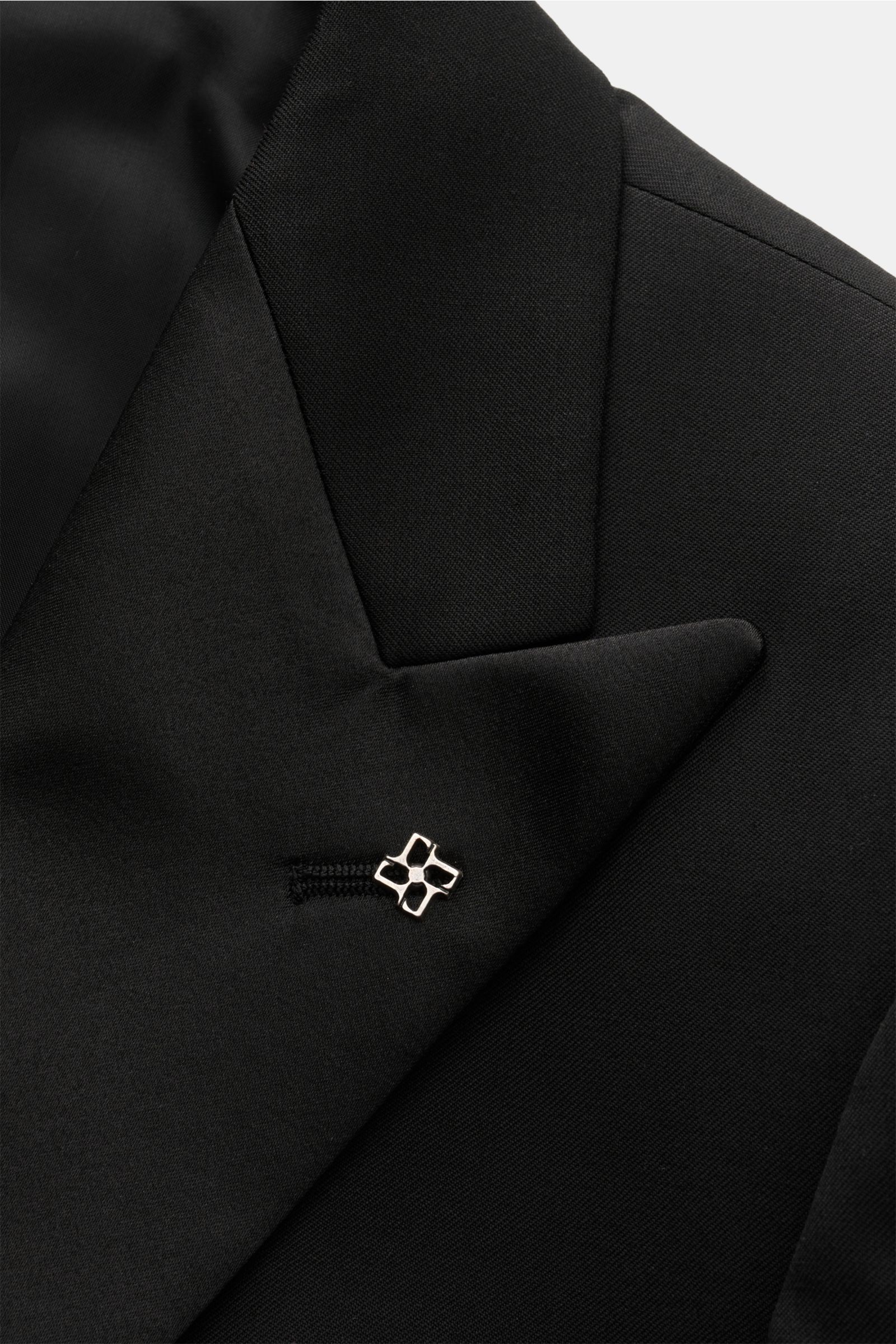 Nahaufnahme des taillierten, schwarzen Tagliatore Smoking 'Napoli' mit Spitzrevers, Satinspiegel und labeltypischem Pin, feine Köperstruktur.