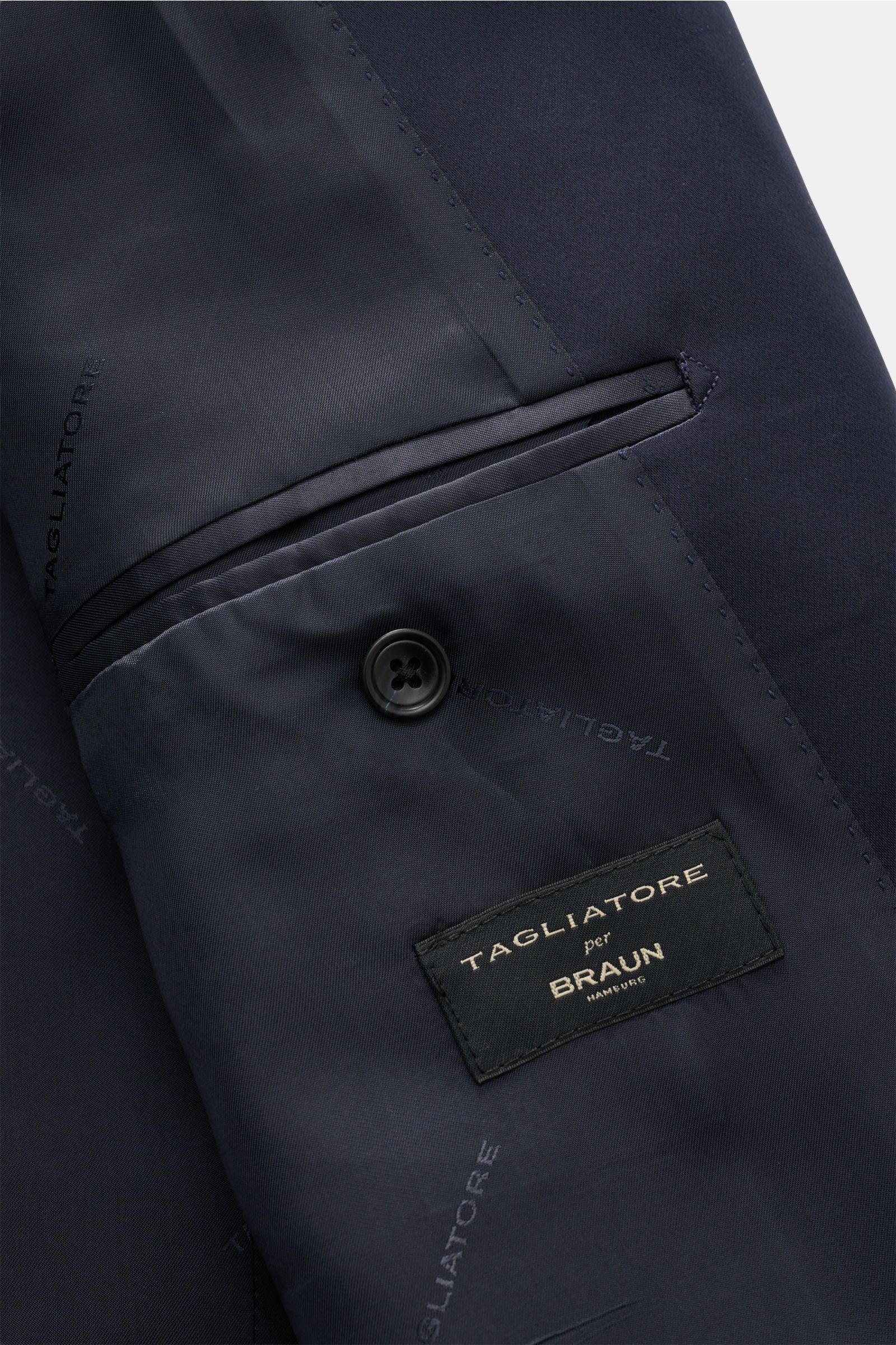 Close-up inside view of the Tagliatore Tuxedo navy showing the smooth satin lining, breast pocket, and branded label, photographed from above.