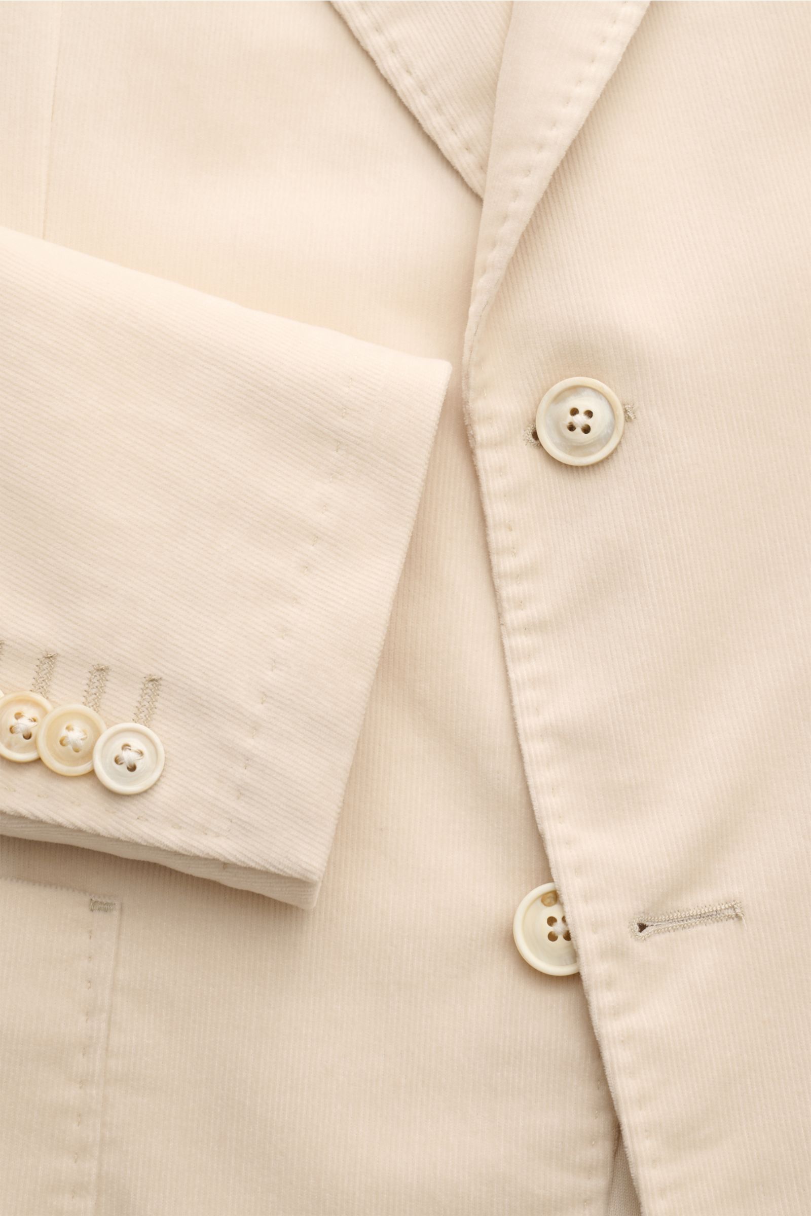 Close-up front view of the Windsor Corduroy jacket 'Gio' cream showing fine corduroy pure cotton fabric, soft touch, slim fit, step lapel, two-button style, classic breast pocket, patch hip pockets, kissing buttons on cuff, side vents at back, unconstruct