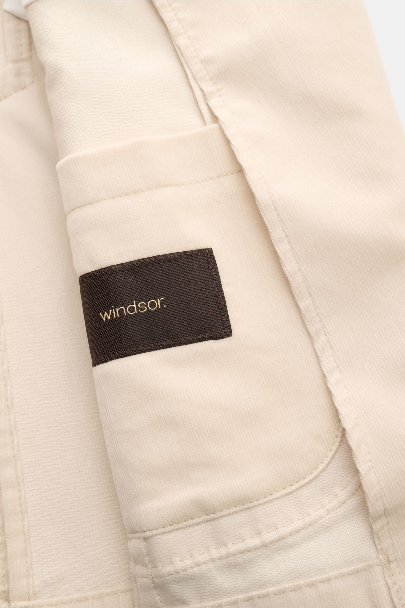 Close-up inside view of the Windsor Corduroy jacket 'Gio' cream showing fine corduroy made of pure cotton, soft touch, slim fit, step lapel, two-button style, classic breast pocket, patch hip pockets, kissing buttons, side vents at the back, unconstructed