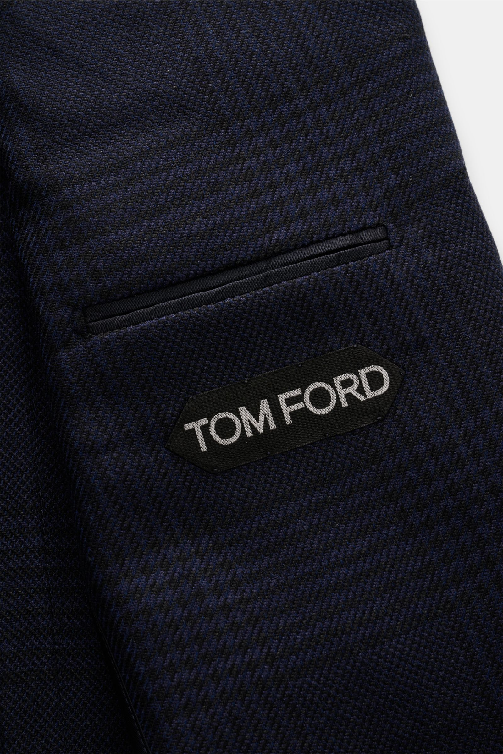 Close-up of Tom Ford Sakko 'Shelton' navy/schwarz kariert showing textured Glencheck fabric and chest pocket with TOM FORD label, photographed from the front.

Purer Luxus von TOM FORD: Der Klassiker 'Shelton' mit edgy Silhouette und dezentem Glencheck