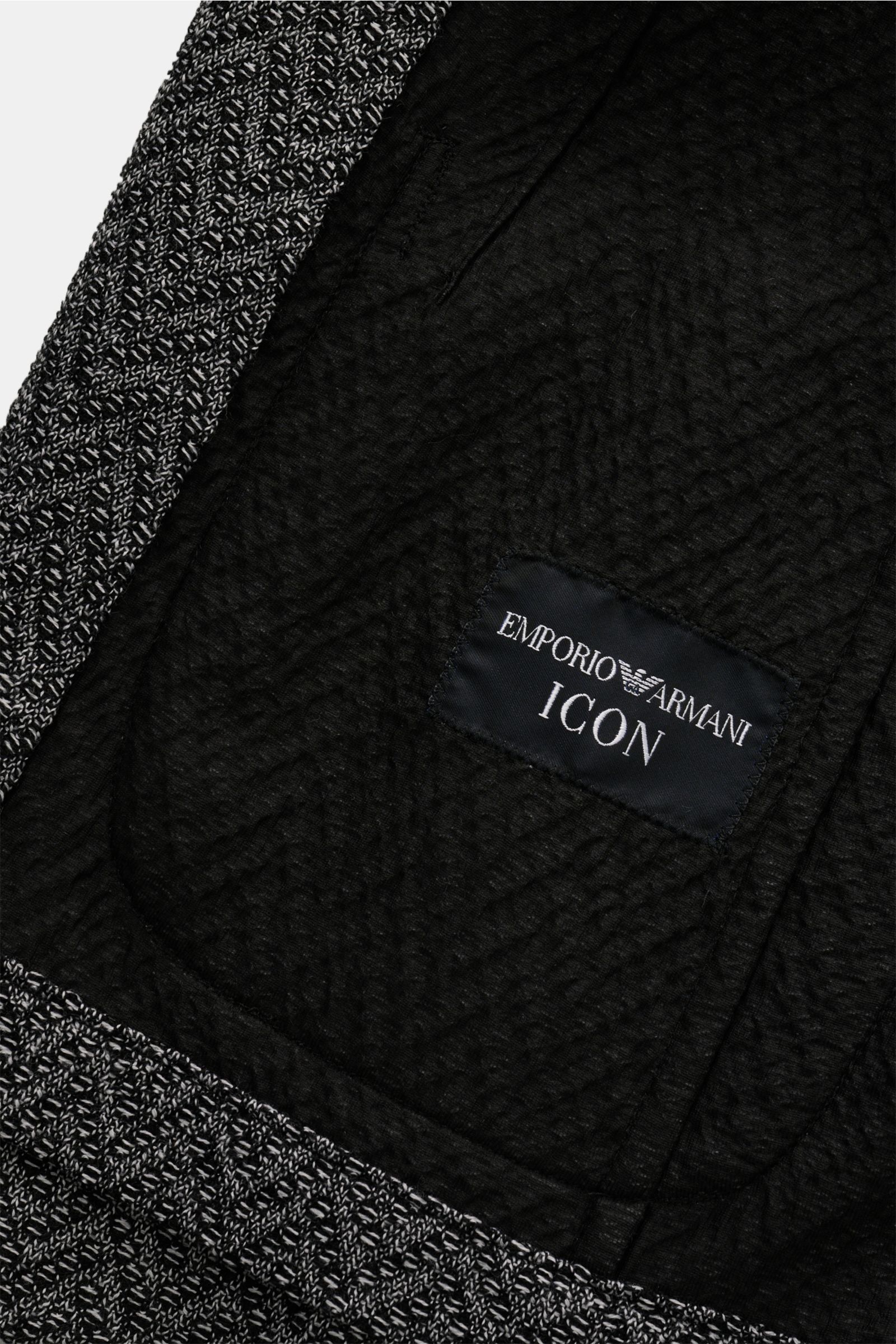 Close-up inside view of the Emporio Armani Strickblazer schwarz/weiß gemustert, showing black lining and brand label. 

Description: Edles Piece mit Twist von EMPORIO ARMANI: Mit diesem Blazer aus feinem und leichtem Strukturstrick aus reiner Wolle lie
