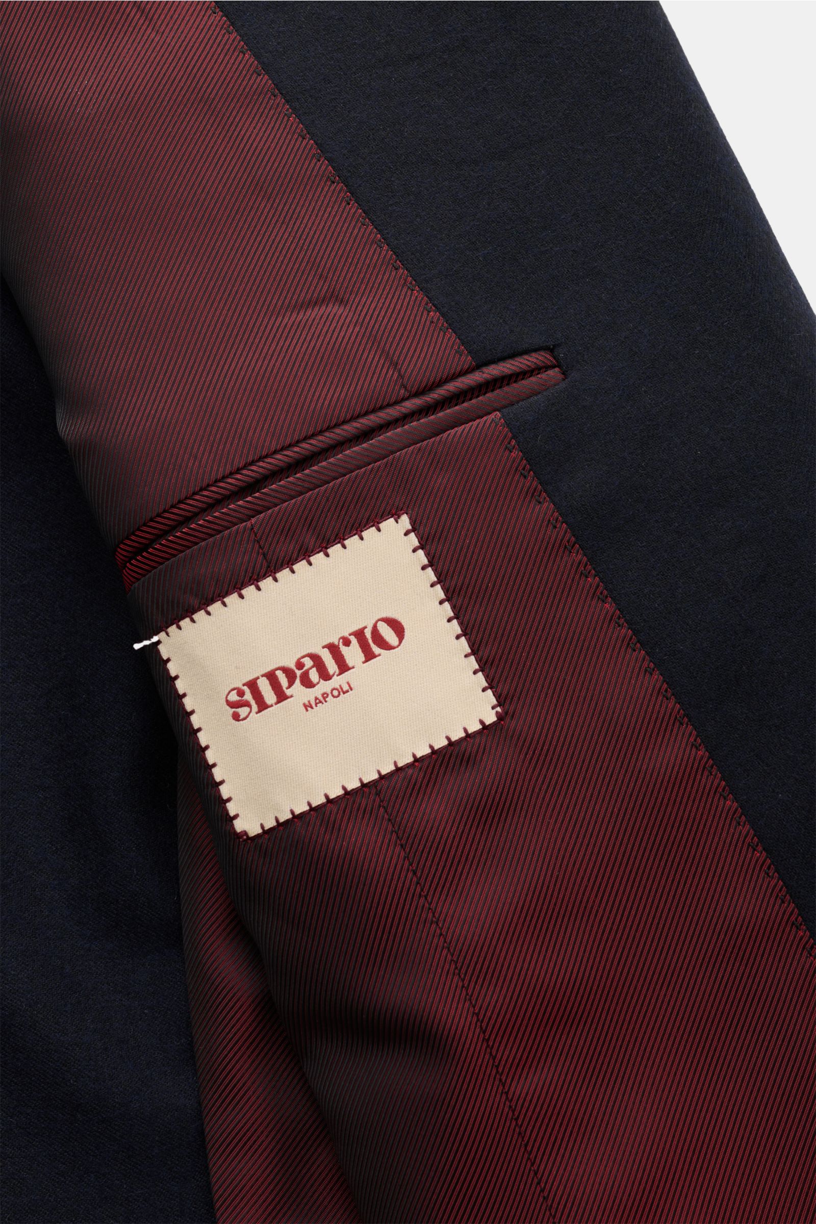 Close-up interior view of Sipario Sakko 'Ivan' navy showing burgundy striped lining with a stitched beige label, highlighting elegant craftsmanship and fabric mix.