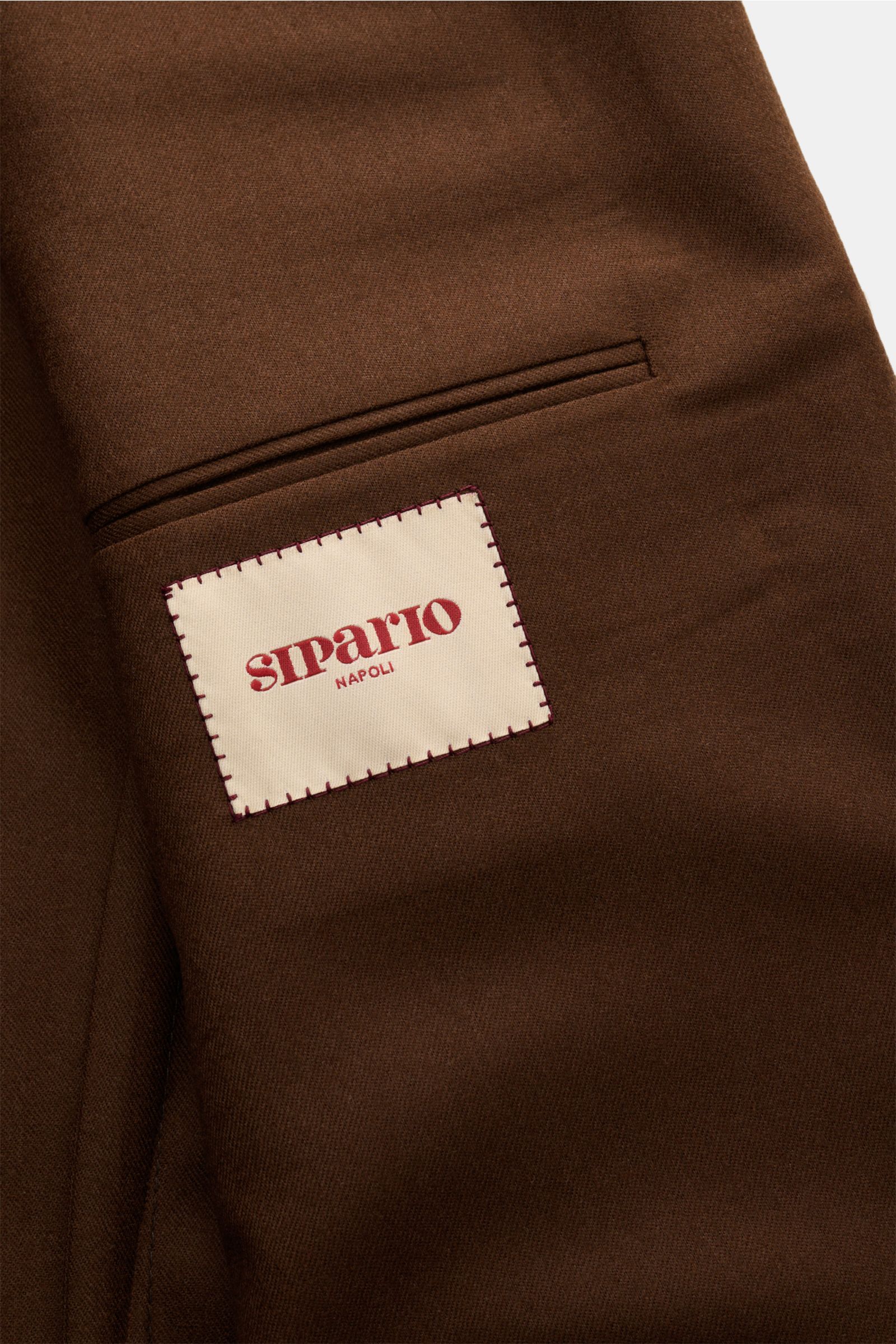 Close-up view of the inner pocket and label of the Sipario Sakko 'Ginza' braun, a slim fit, half-lined brown wool blazer featuring unconstructed body, unfinished sleeve cuffs, and tailored three-button style. Der Inbegriff von Unconstructed – also der 