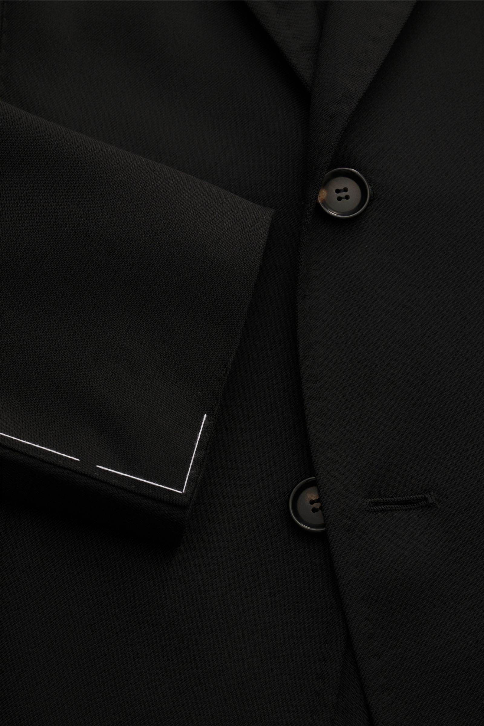 Close-up front view of the Sipario Sakko 'Ginza' navy jacket, showing the slim fit, tonal herringbone pattern, three-button style, and unfinished sleeve cuffs. Eleganz, ganz ohne Schwere: Das Sakko 'Ginza' von SIPARIO interpretiert klassische Form neu – m