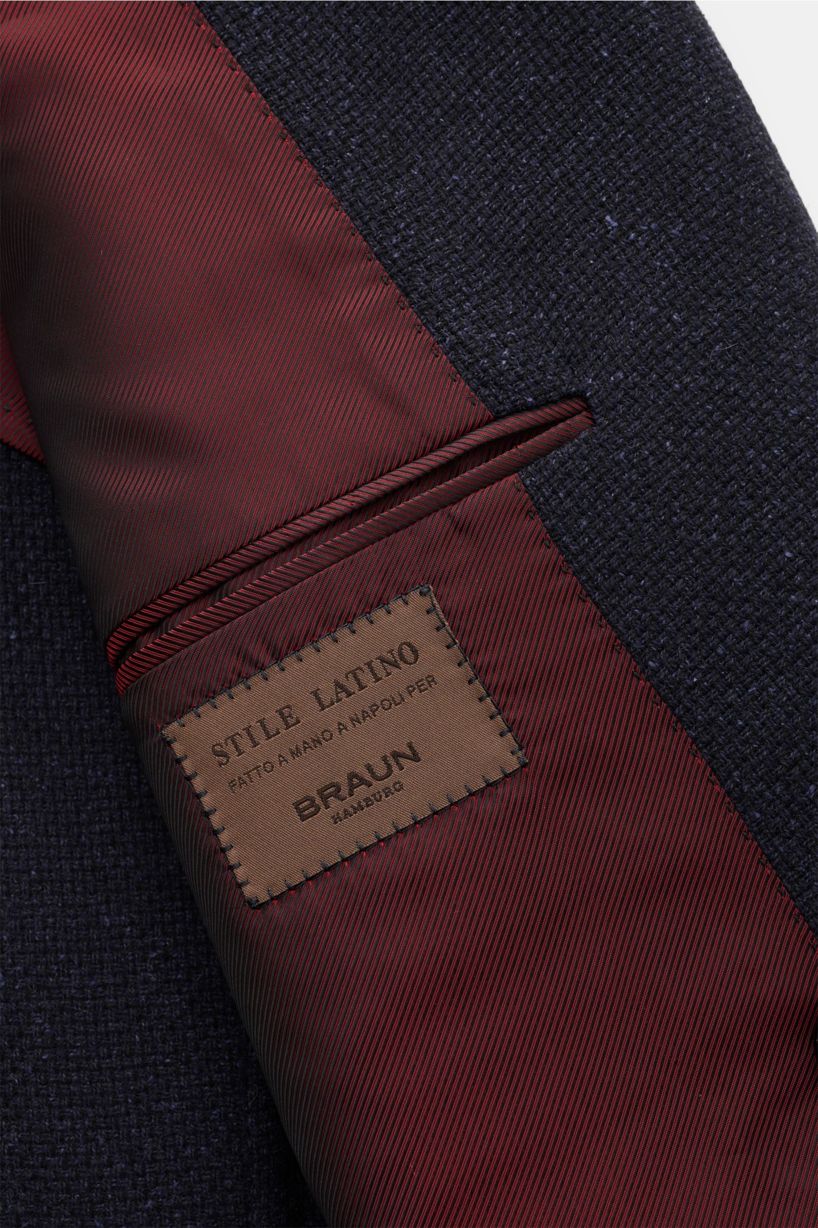 Close-up image of the inside pocket and label of the Stile Latino Smart-casual jacket 'Andrea' dark navy, showing the textured dark navy Panama fabric and burgundy striped lining. An eye for detail and an impeccable finish is what we have come to expect f