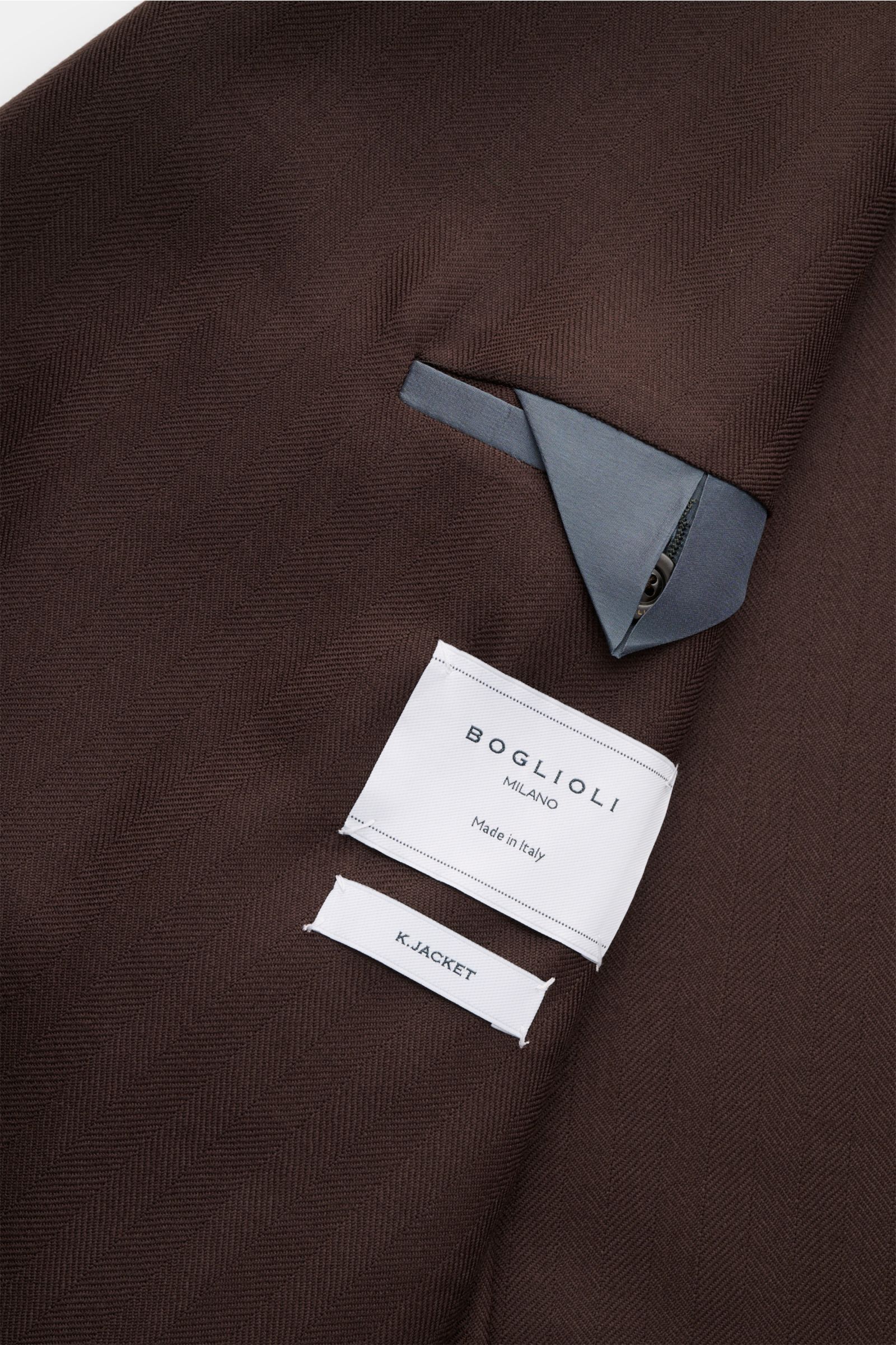 Close-up inside view of Boglioli Sakko 'K. Jacket' dunkelbraun showing tonal herringbone pure wool fabric, two inner pockets, and label, featuring Slim Fit, two-row three-button style, peaked lapel, classic breast pocket, patch hip pockets, kissing button
