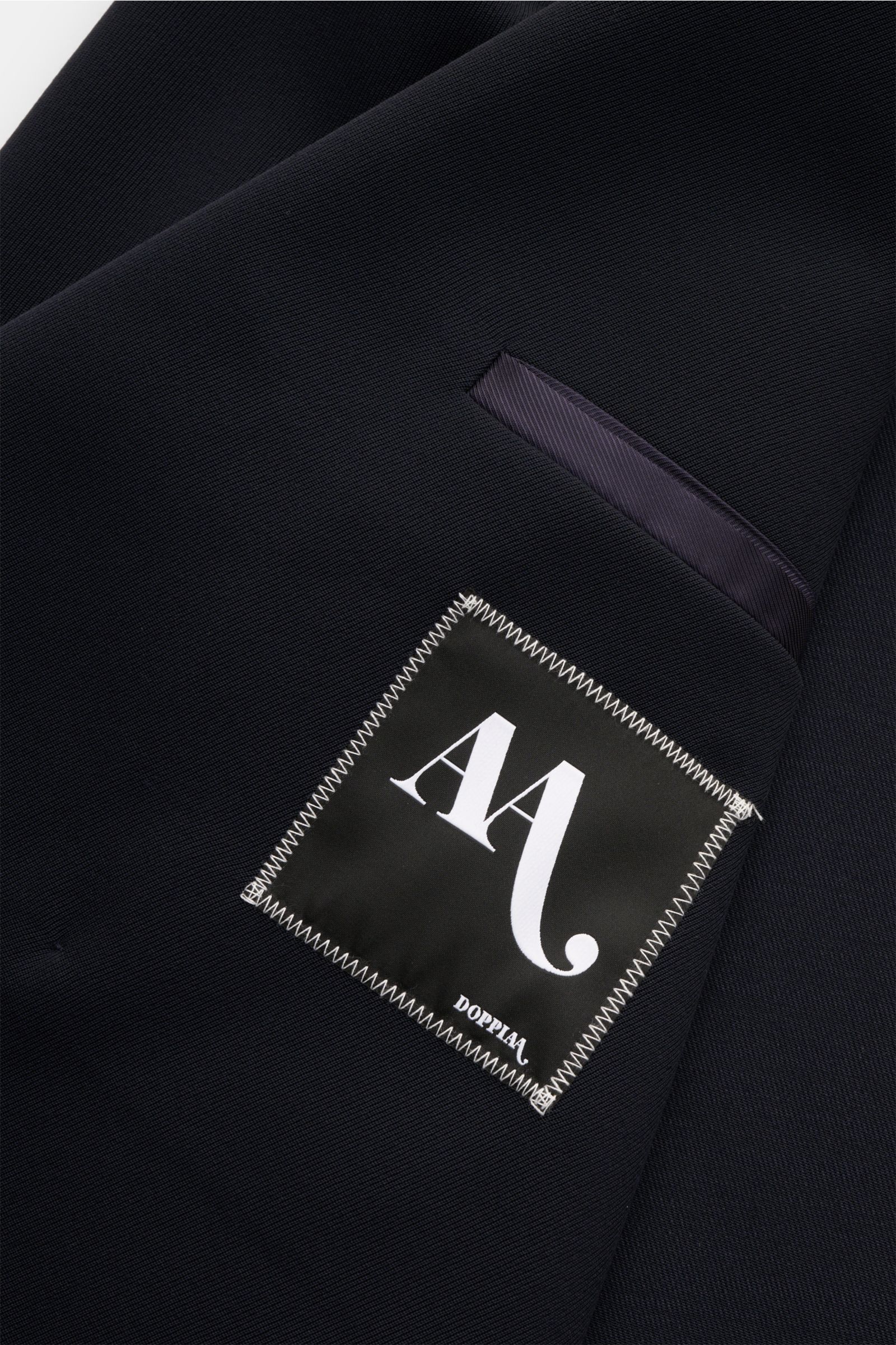 Close-up of the navy Doppiaa Sakko 'Aanversa' showing fabric texture and label, photographed from a top-down perspective. Schnelles Styling gefällig? Das stilvolle, maritim anmutende Sakko 'Aanversa' von DOPPIAA aus edlem Woll-Twill im zweireihigen Stil m