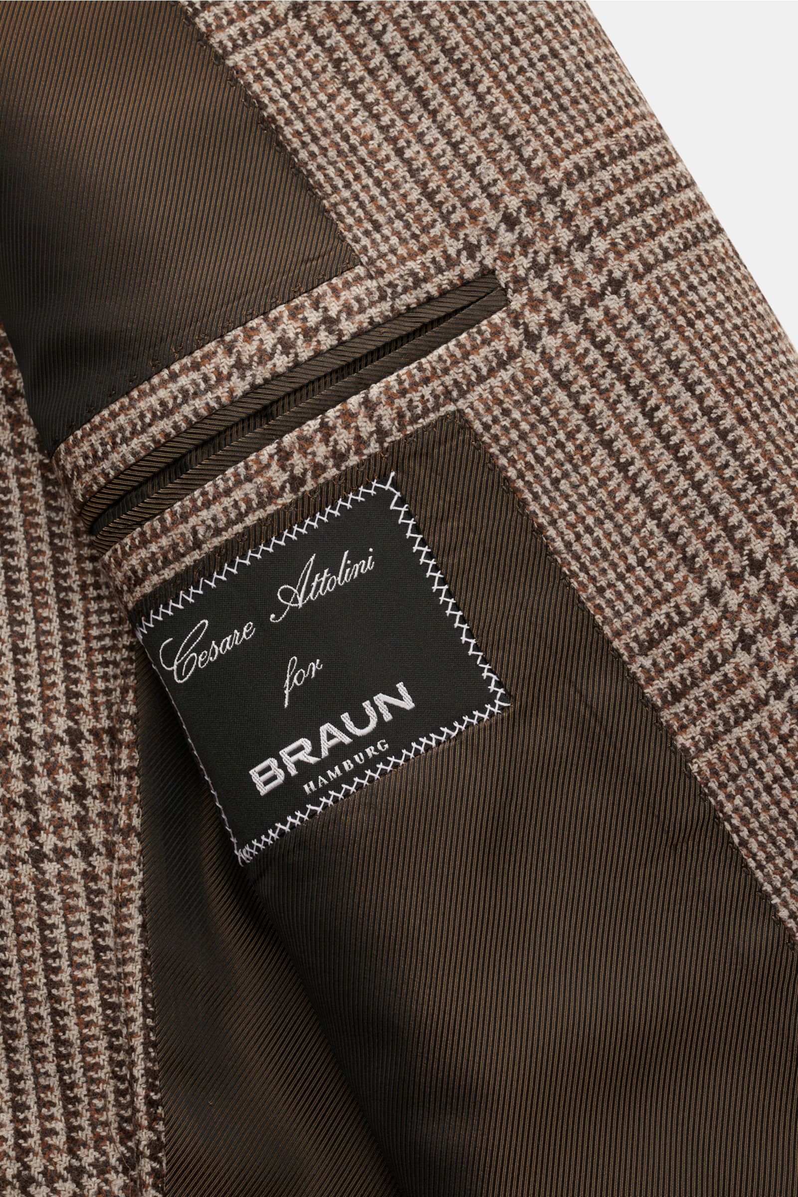 Close-up of the inside pocket and label of the Cesare Attolini Cashmere Sakko braun/beige kariert, showing brown/beige Glencheck pattern and fine stitching from a top-down perspective. Gönnen Sie sich Luxus aus dem Hause CESARE ATTOLINI: Dieses zeitlos