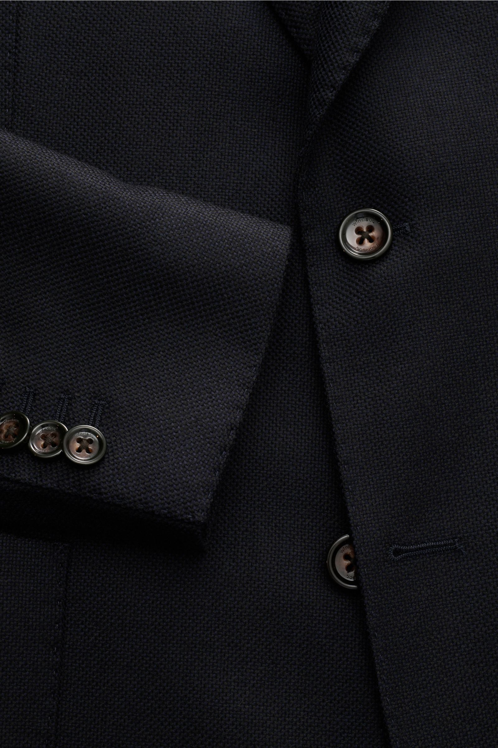 Close-up front view of Windsor Sakko 'Sora' dark navy jacket showing texture, buttons, and sleeve details. Features: Panama aus reiner Wolle, weicher Griff, Slim Fit, fallendes Revers, Zwei-Knopf-Stil, klassische Brusttasche, aufgesetzte Hüfttaschen, Kiss