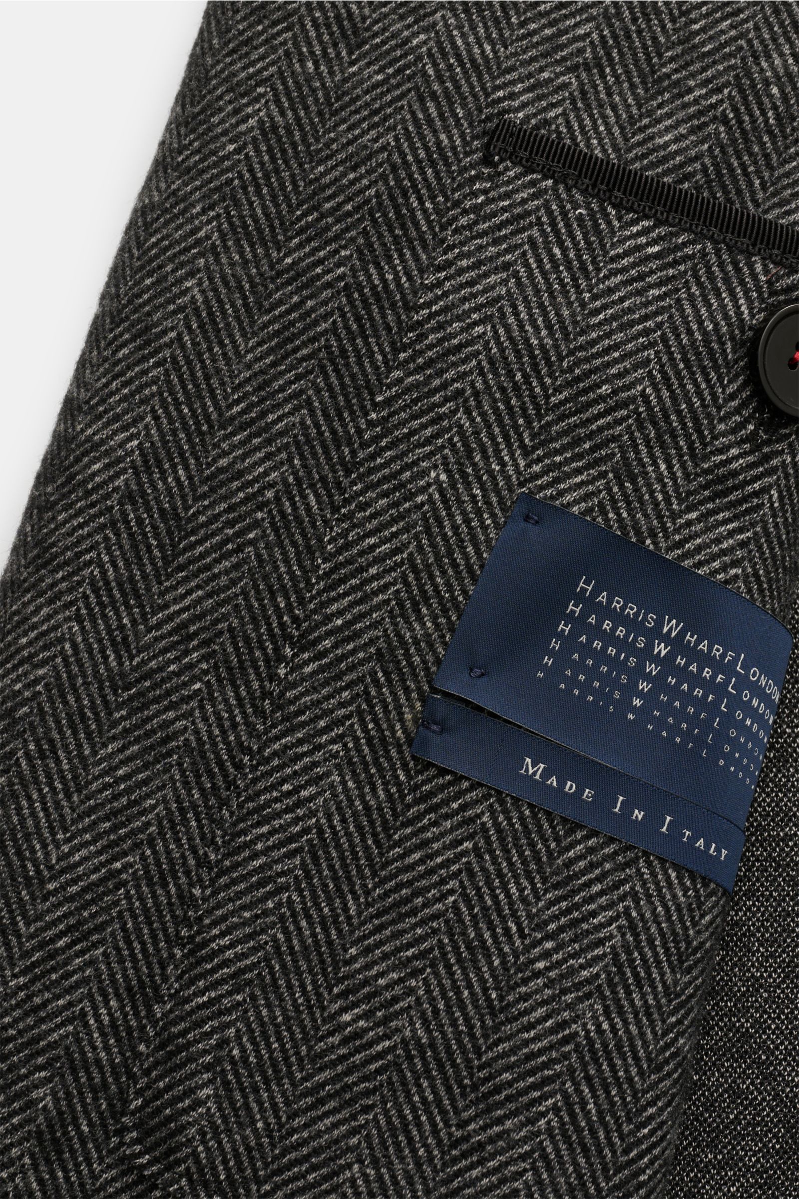 Nahaufnahme des Harris Wharf London Sakkos dunkelgrau gemustert mit Fischgratmuster, sichtbare Innenansicht mit Label, zwei Knöpfen, fallendem Revers, Brust- und Hüfttaschen, Slim Fit.