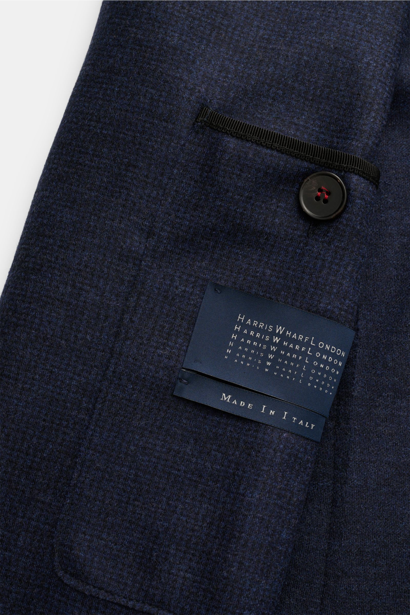 Close-up view of the Harris Wharf London Sakko dunkelblau kariert showing the dark blue checked pure virgin wool fabric, black button, and inner pocket with brand label 'Made in Italy.'

Leicht und weich präsentiert sich die reine Schurwolle in diesem 