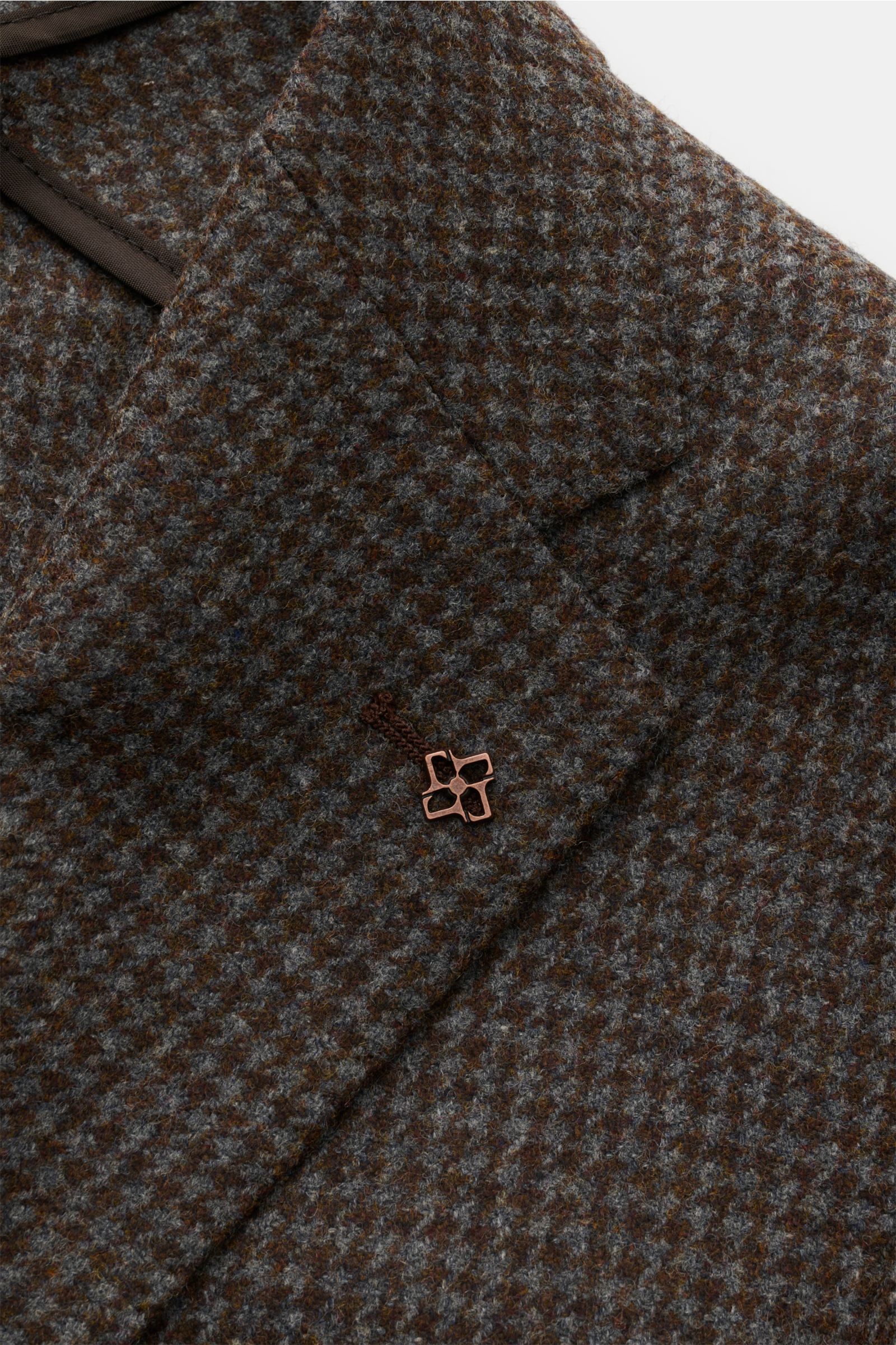 Nahaufnahme des braun/graublau karierten Tagliatore Sakko 'Monte Carlo' mit Unconstructed-Verarbeitung aus reiner Super 110'S Wolle, weichem Griff, fallendem Revers, markentypischem Pin, klassischer Brusttasche und aufgesetzten Hüfttaschen, fotografiert v