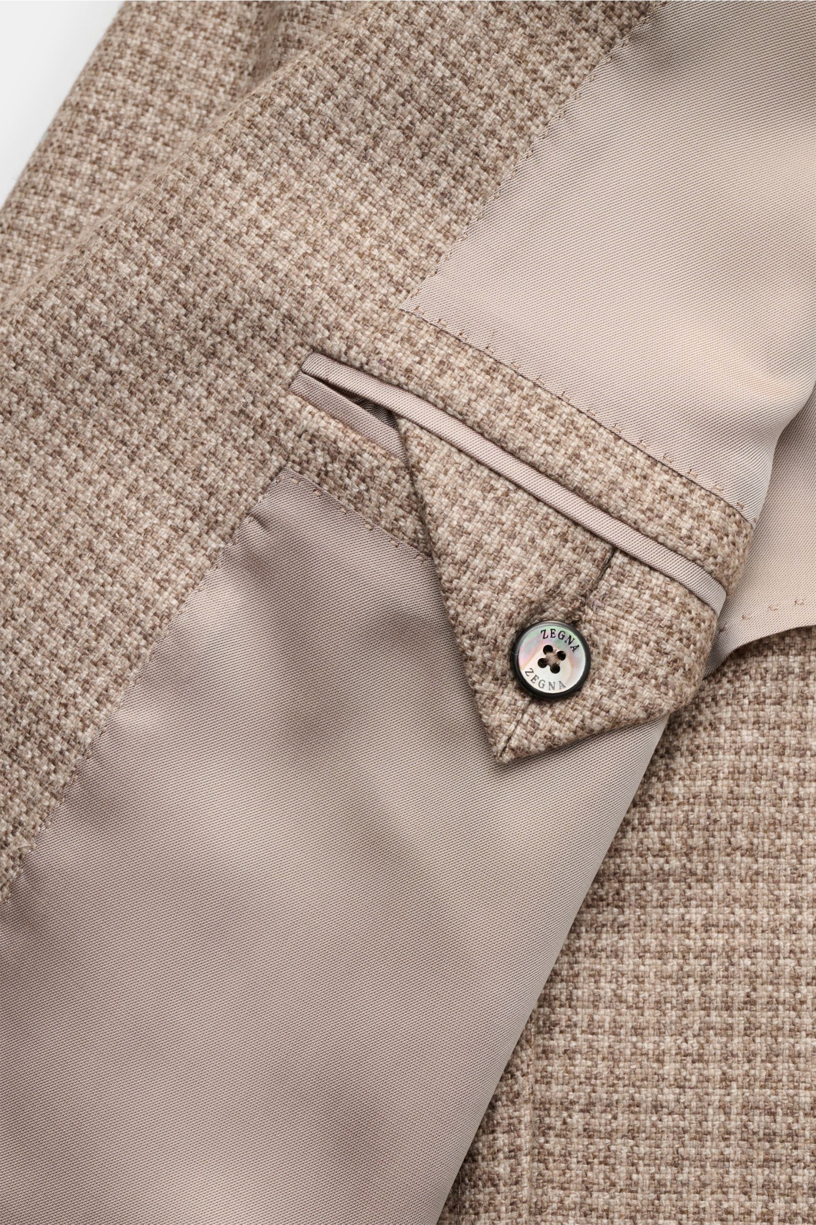Close-up inside view of the Zegna Smart-casual jacket grey-brown/beige patterned showing silk-cashmere blend, houndstooth weave, and branded button.

This smart-casual jacket made of silk and cashmere by ZEGNA, featuring a subtle houndstooth weave patt