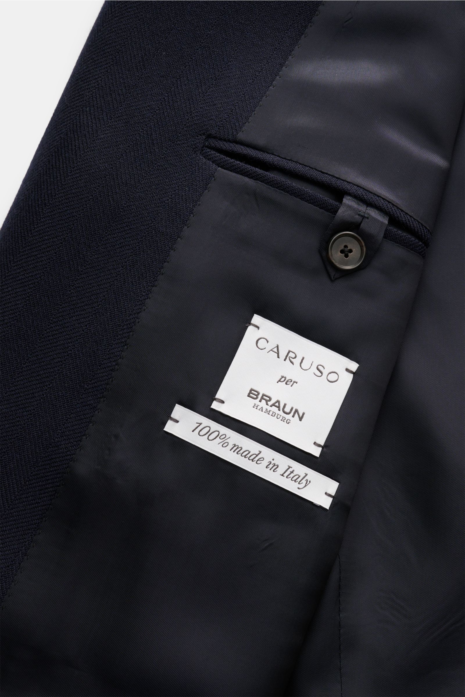 Close-up inside view of Caruso Sakko 'Aida' navy showing fine wool herringbone texture, smooth lining, and inner pocket with button.