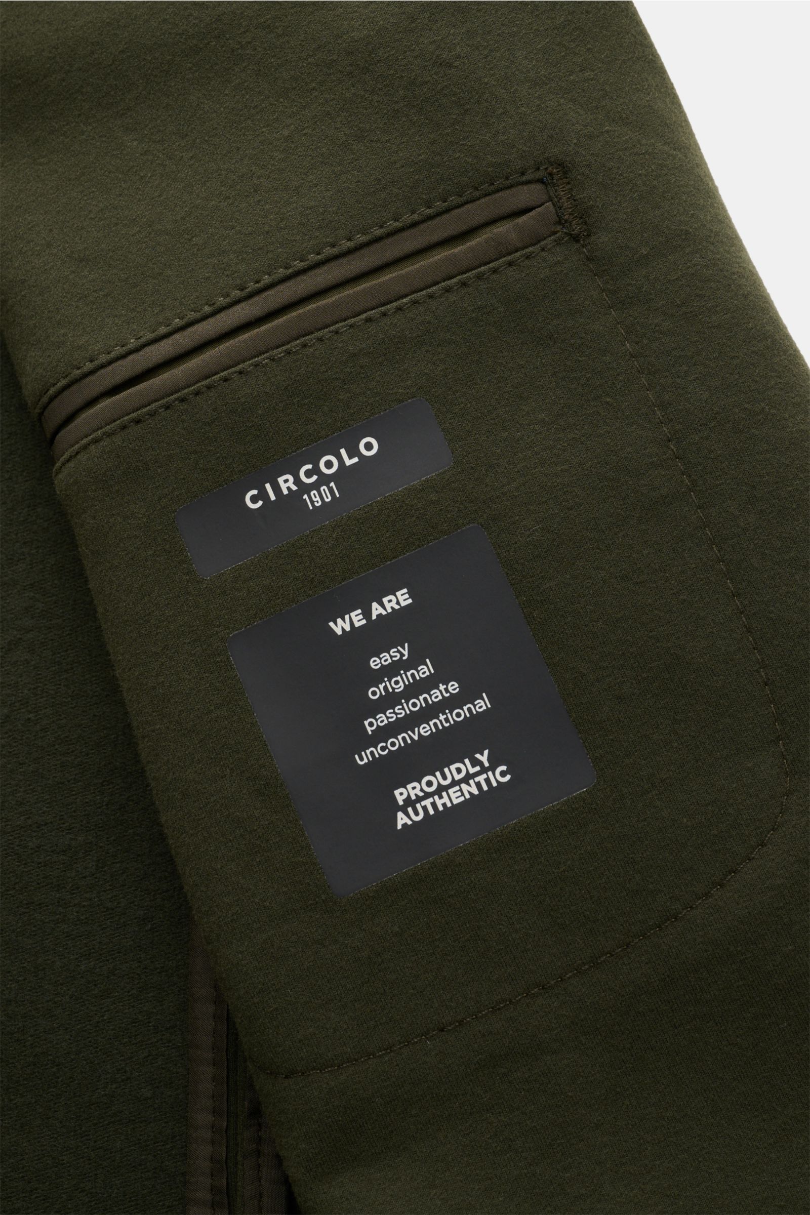 Nahaufnahme des graugrünen Circolo 1901 Jersey-Sakkos aus elastischer Baumwolle, Slim Fit mit Label auf der Innentasche, fotografiert aus schräger Perspektive.