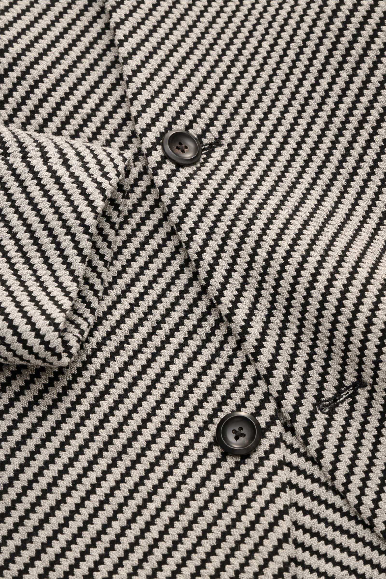 Emporio Armani Sakko hellgrau/schwarz gemustert close-up from above showing zigzag pattern, buttons, and fabric texture. Stilvoll durch den Frühling: Das Sakko von EMPORIO ARMANI verbindet zeitloses Design mit leichter Materialität.Mix aus 