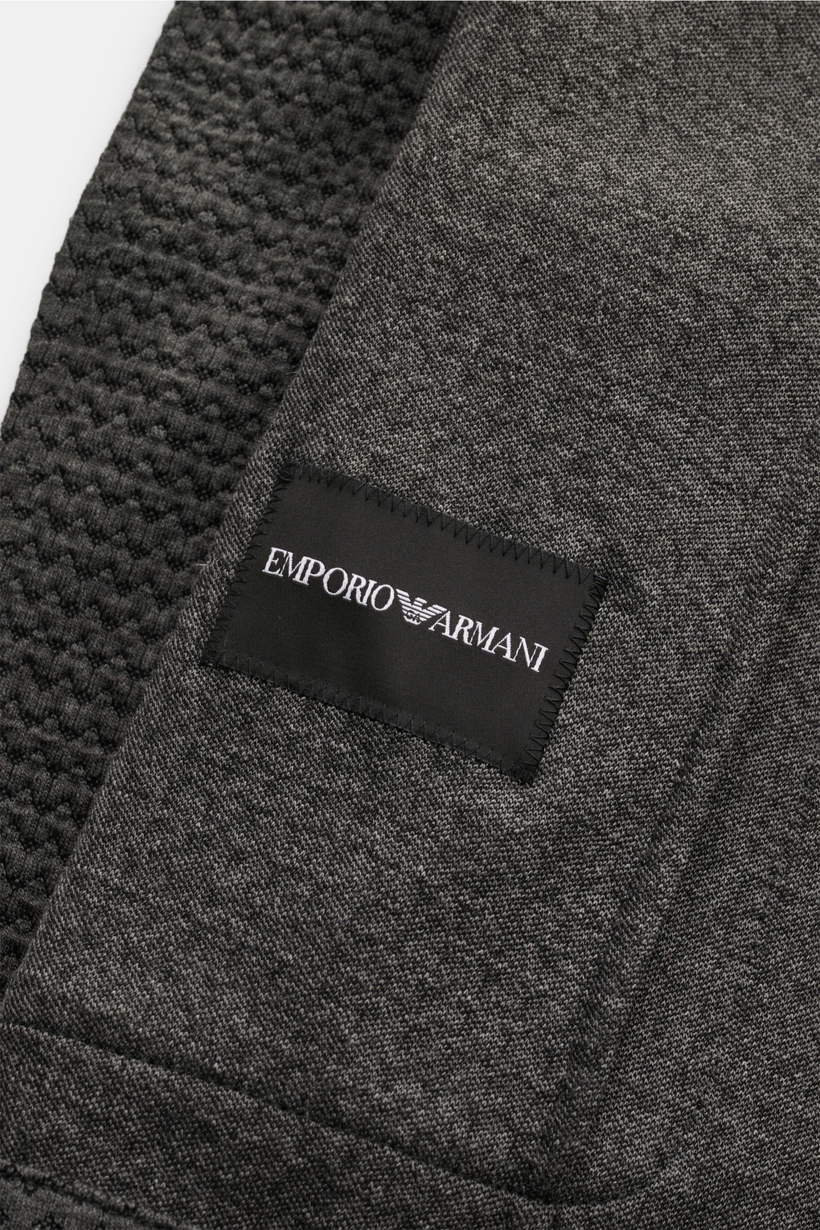 Close-up front view of the Emporio Armani Strickblazer dunkelgrau meliert showing textured knit patterns and black label on soft wool blend fabric.