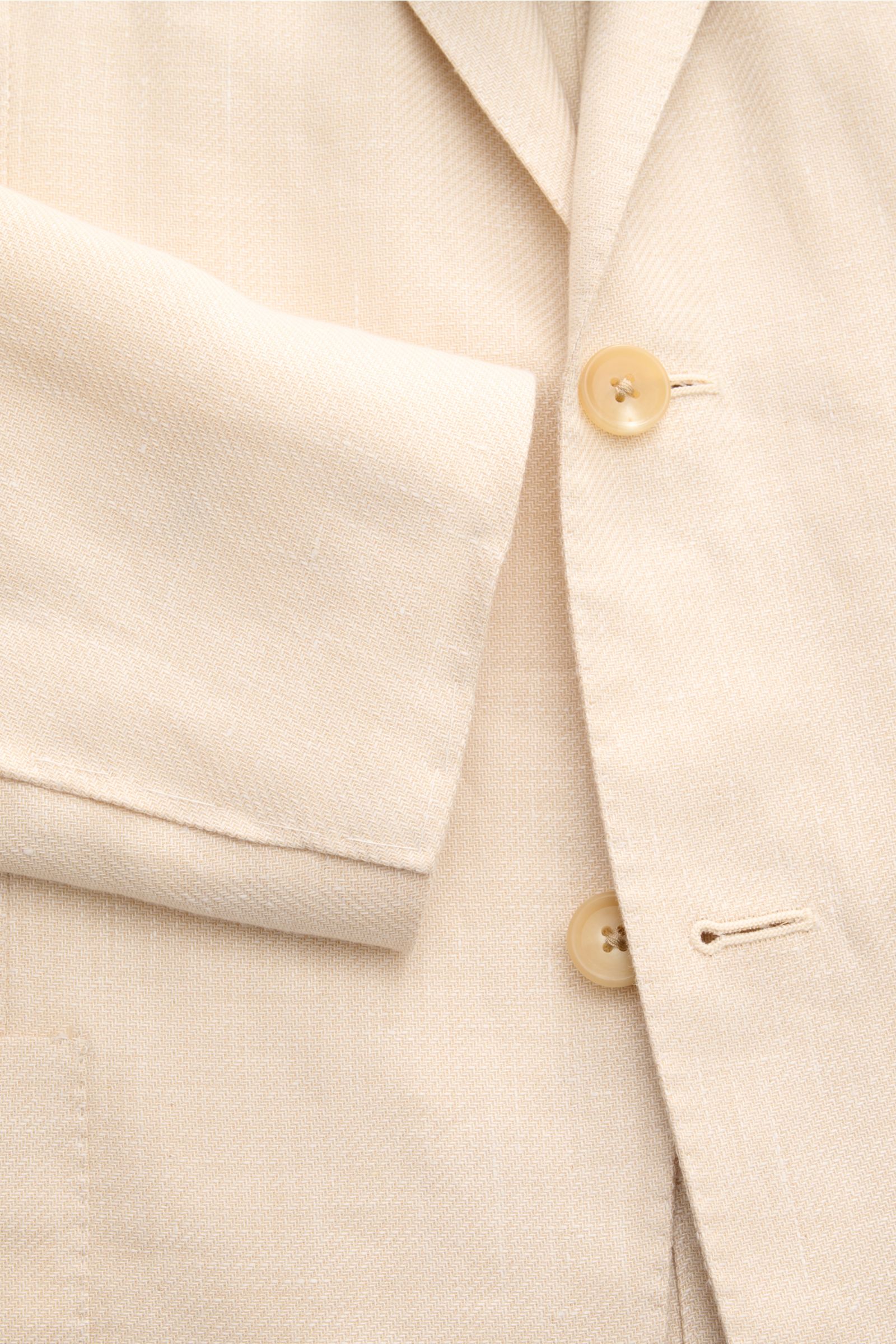 Close-up front view of Corneliani Sakko creme showing soft textured fabric, two cream buttons, and tailored sleeve. Formvollendeter Stil von CORNELIANI: mit optimalem Fit aus italienischer Meisterhand wurde dieses Sakko aus leichtem Lyocell und Leinen gef