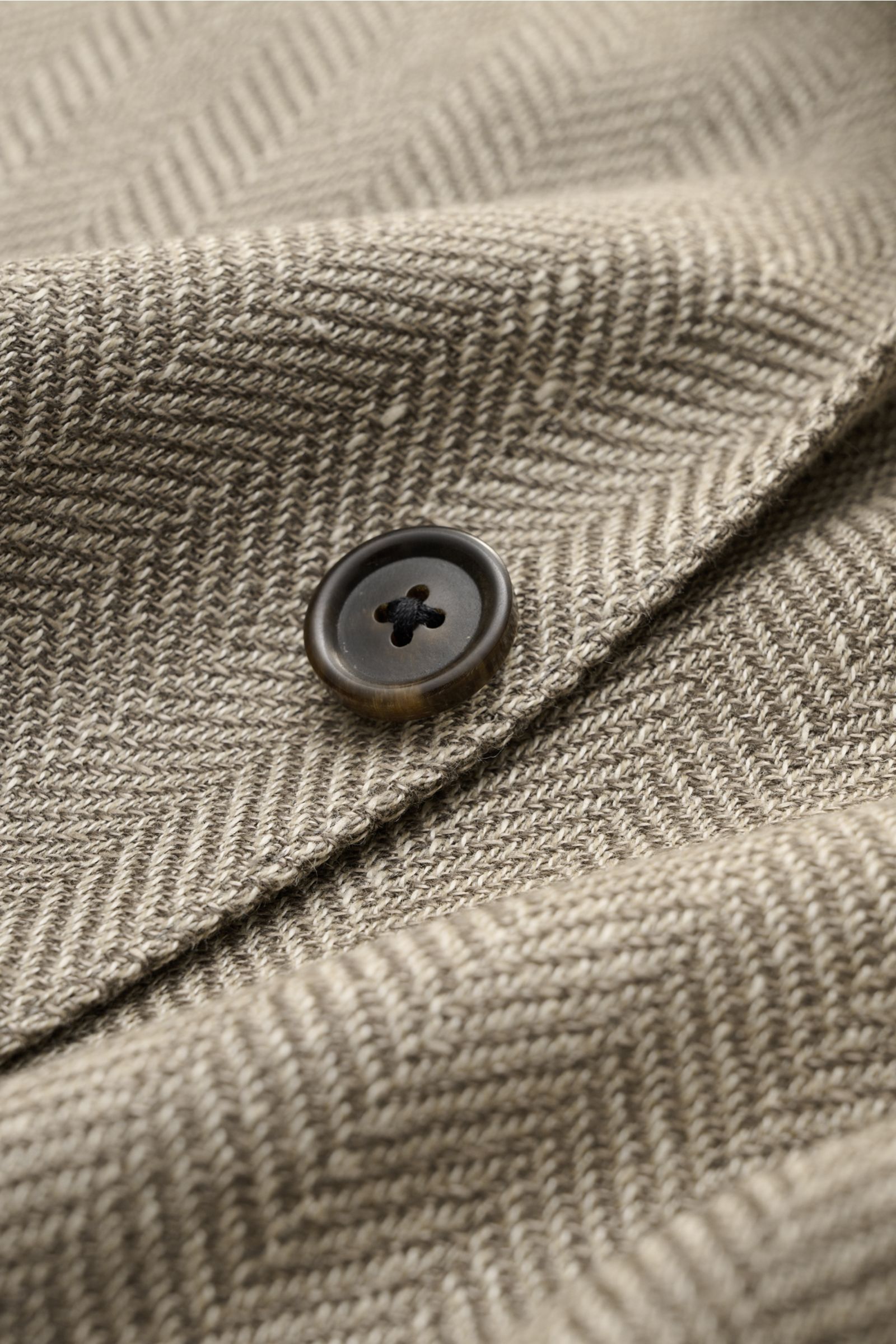 Close-up of taupe patterned fabric and button of Corneliani Sakko taupe gemustert, showing fine wool-linen mix and herringbone weave.

Description: Stilvoll durch die neue Saison: mit optimalem Fit aus italienischer Meisterhand von CORNELIANI wurde die