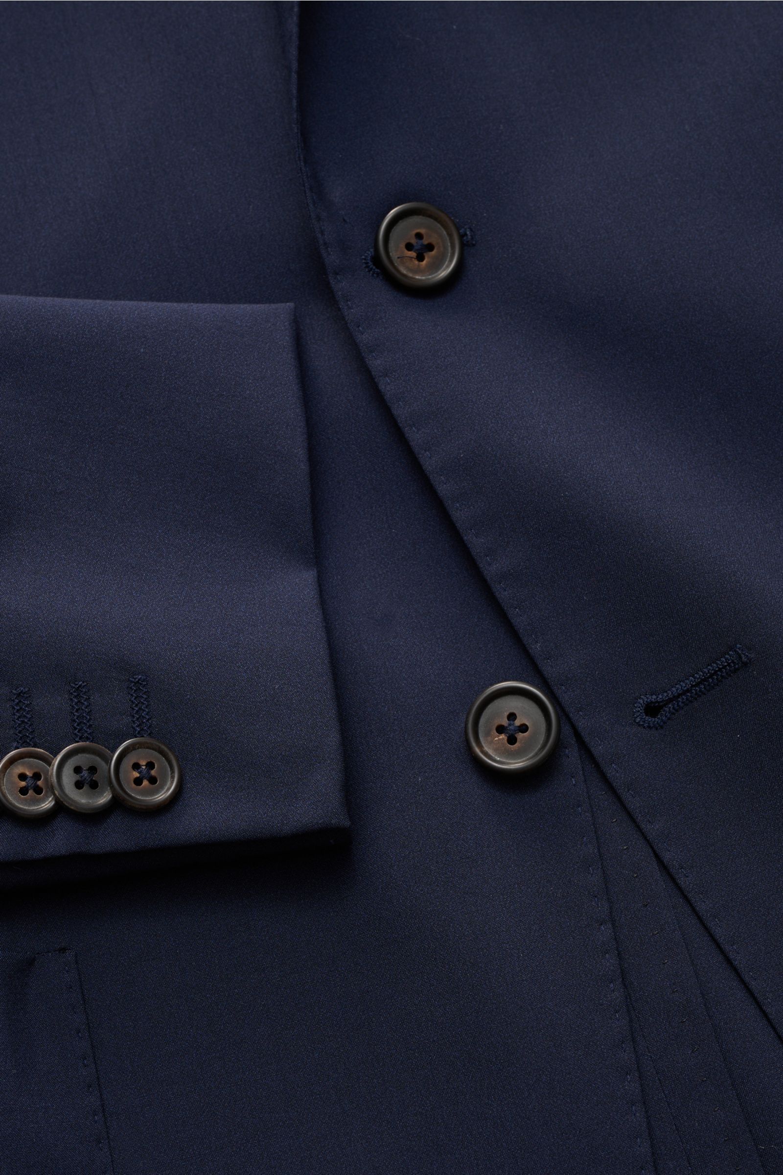 Nahaufnahme des Corneliani Sakko navy aus feinem Wolle-Seiden-Mix, Slim Fit, taillierter Zwei-Knopf-Stil, glatter Griff, Ärmel mit Knöpfen, fallendes Revers, fotografiert von schräger Draufsicht.