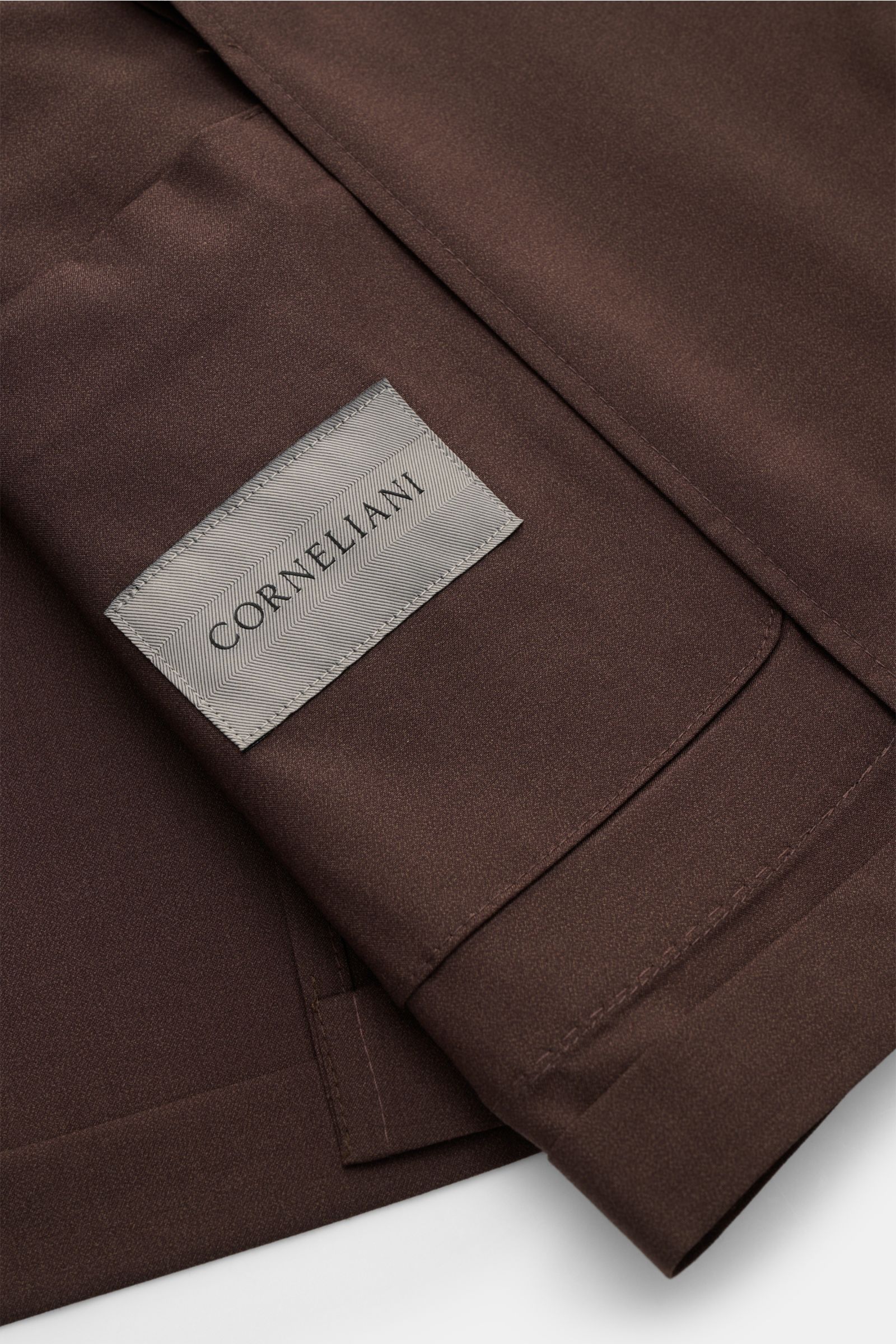 Alt tag (125 characters): Close-up, top-down view of dark brown Corneliani smart-casual jacket fabric and label showing fine wool-silk blend texture.

Description: Easy style all summer long: this smart-casual jacket in a fine wool-silk blend has been 