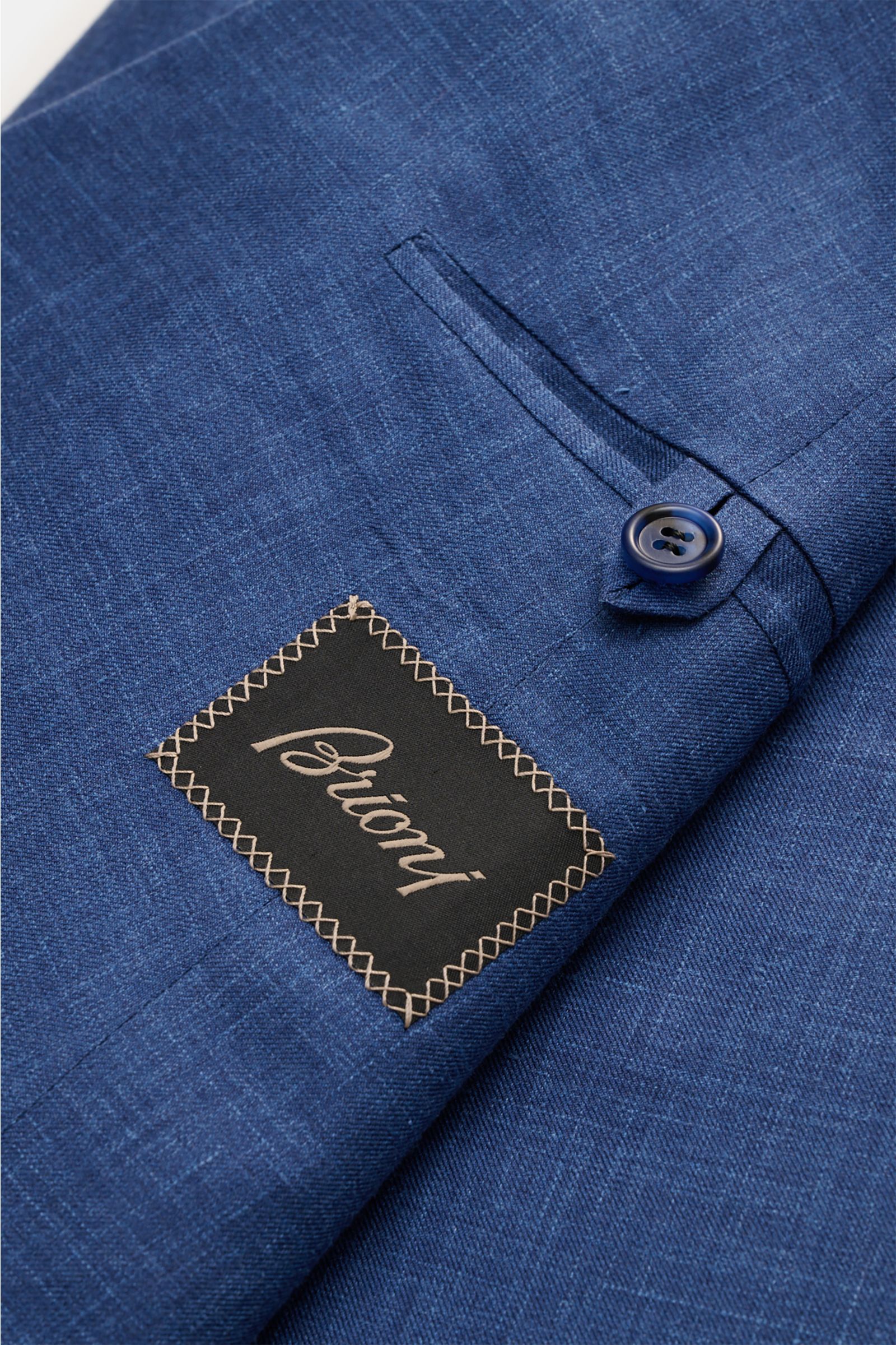 Close-up view of the Brioni Smart-casual jacket 'New Plume' grey-blue mottled fabric, showing detailed texture, button, and label.

Description: A lightweight mottled fabric made from a high-quality blend of silk and cashmere defines the elegant appearanc
