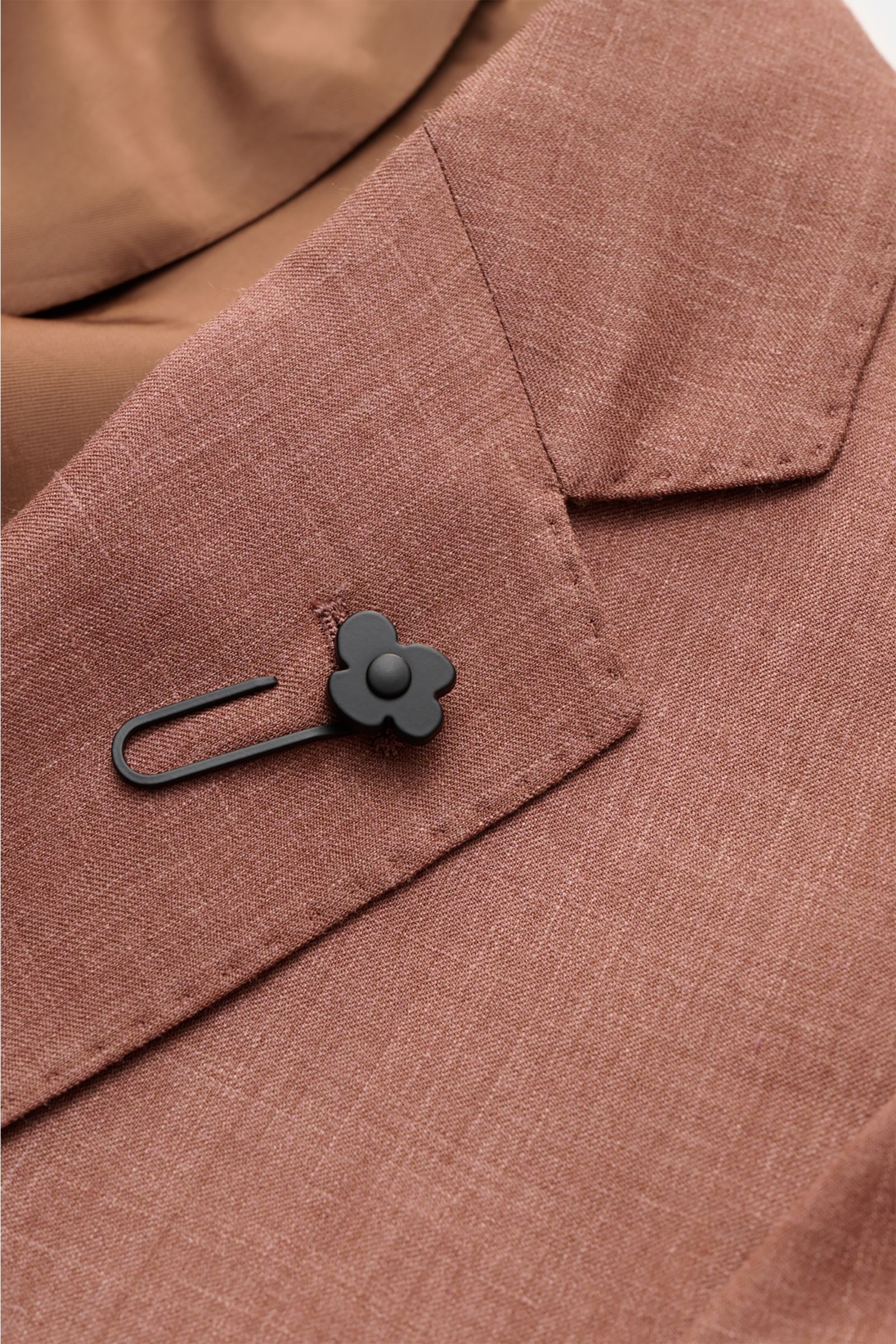 Lardini Sakko braun meliert, Detailaufnahme von schräg oben auf das Spitzrevers mit schwarzem Blumen-Anstecker aus Wolle, Seide und Leinen.