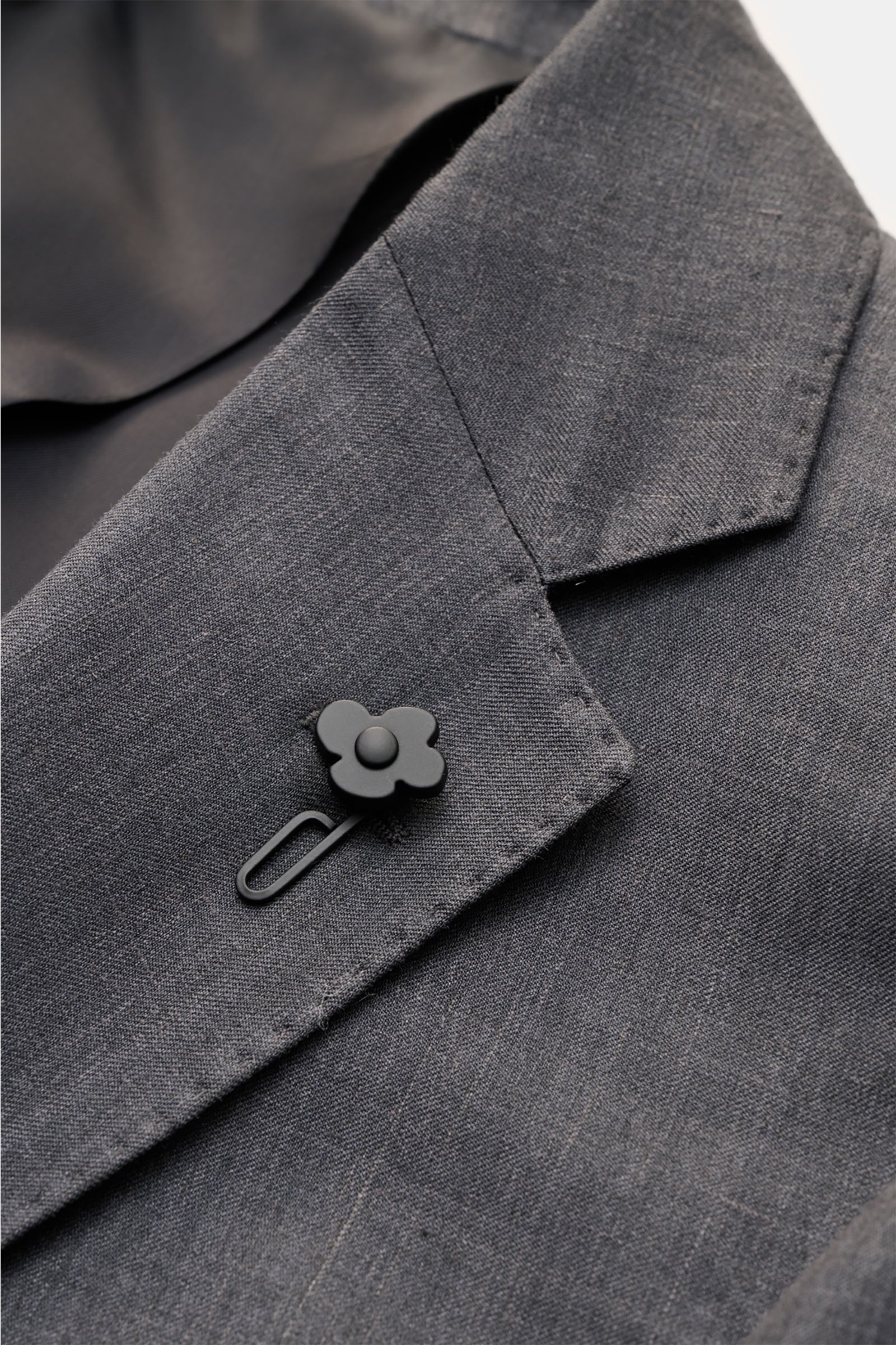 Lardini Sakko dunkelgrau meliert, Detailaufnahme von oben schräg, feine Woll-Seide-Leinen-Qualität mit Blüten-Anstecker am Spitzrevers.